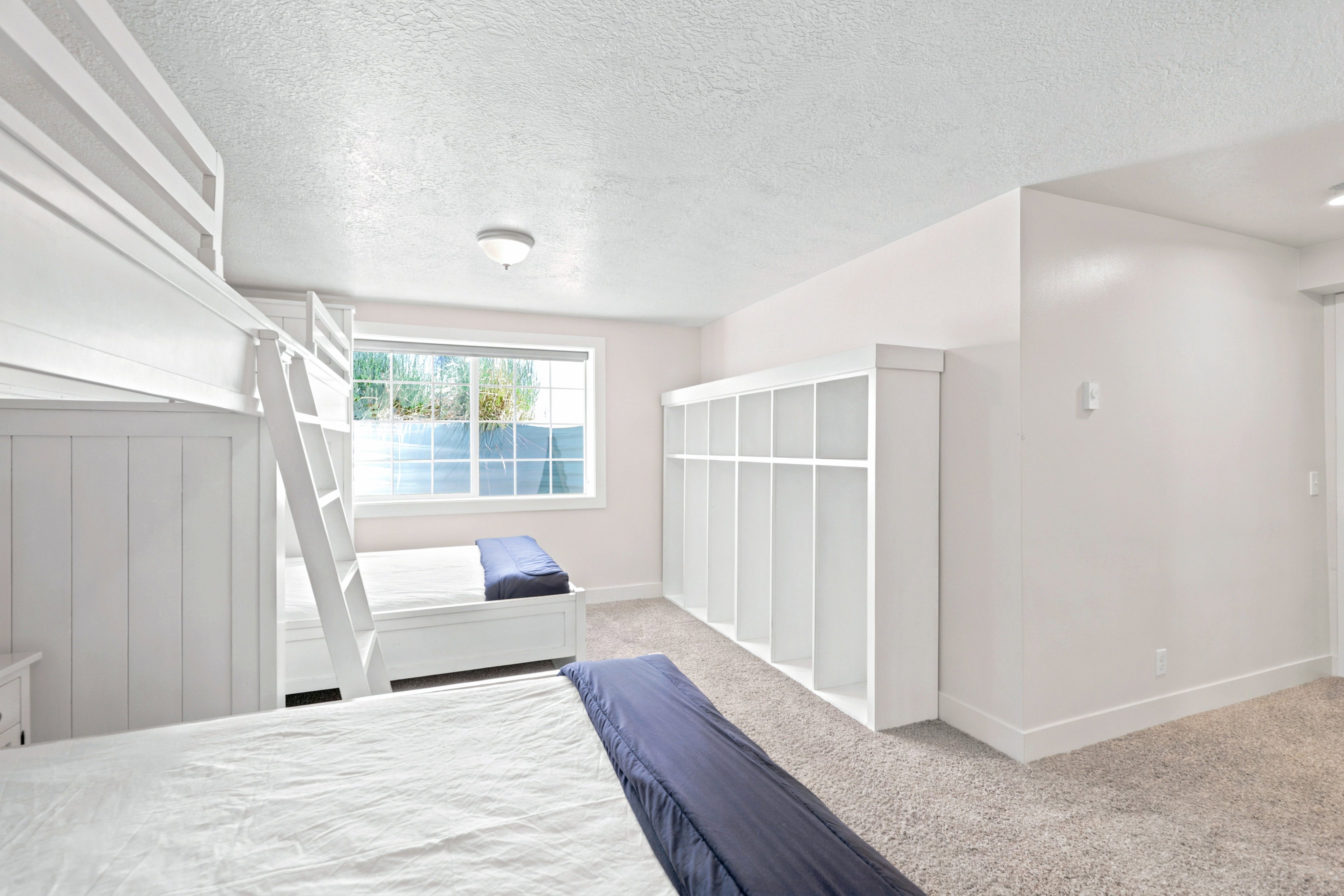 Carpeted room featuring a large window, built-in storage shelving, and light-colored walls