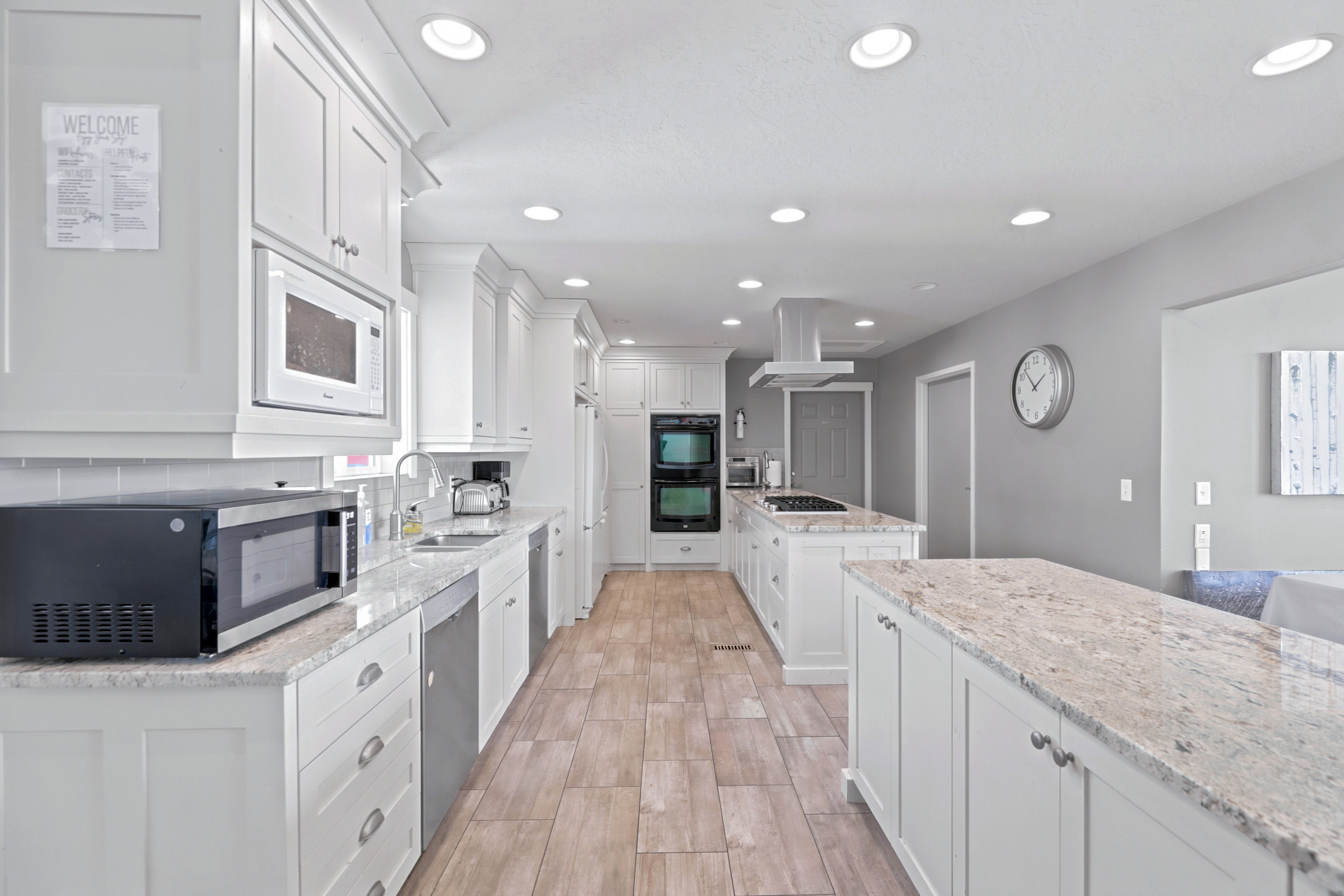 Spacious kitchen featuring white cabinetry, light-toned countertops, and wood-finish flooring