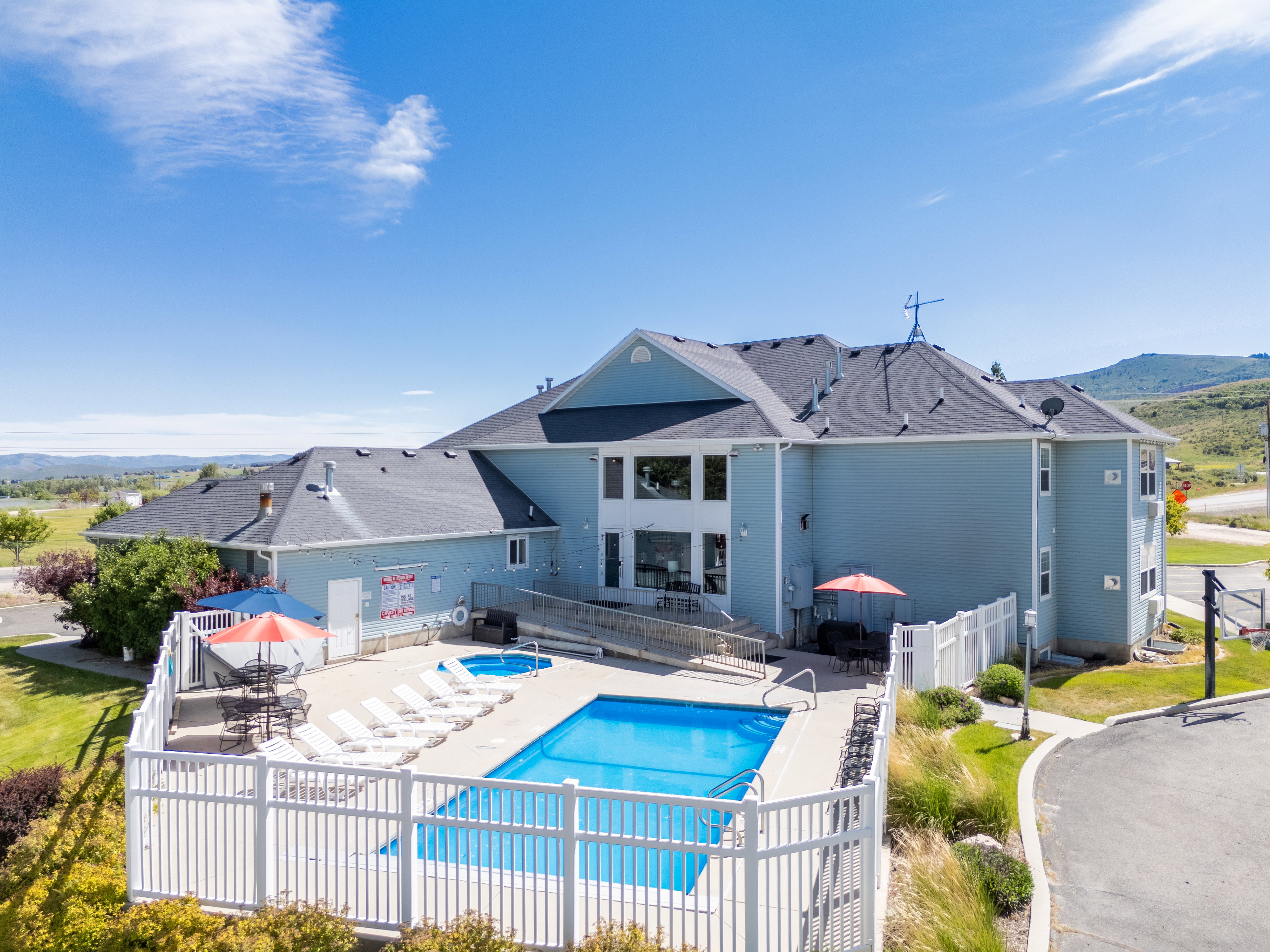Outdoor swimming pool area featuring a rectangular pool, integrated hot tub, and a surrounding white picket fence