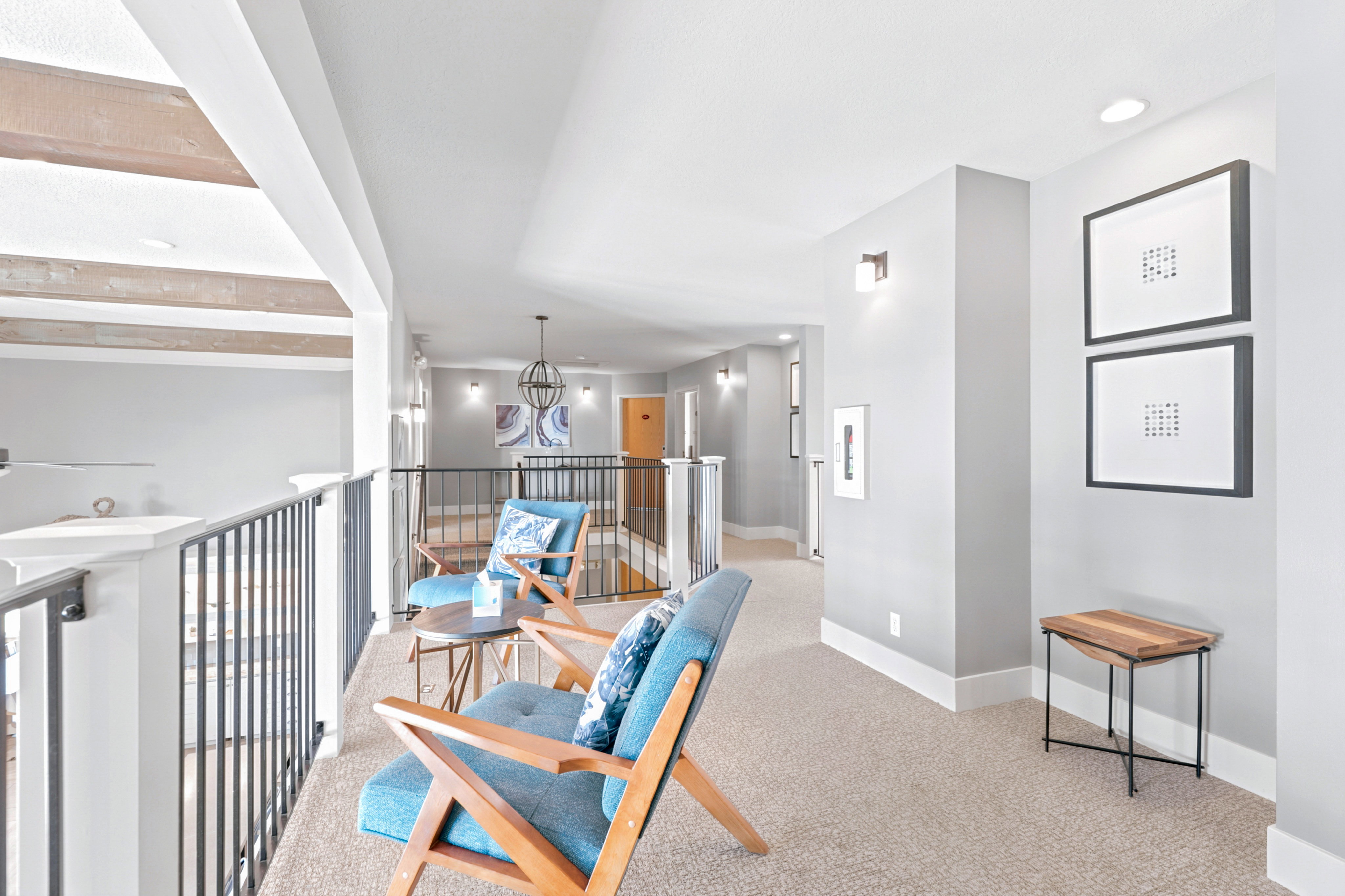 Upper-level hallway featuring neutral carpeting, white trim, and light gray walls with sconce lighting