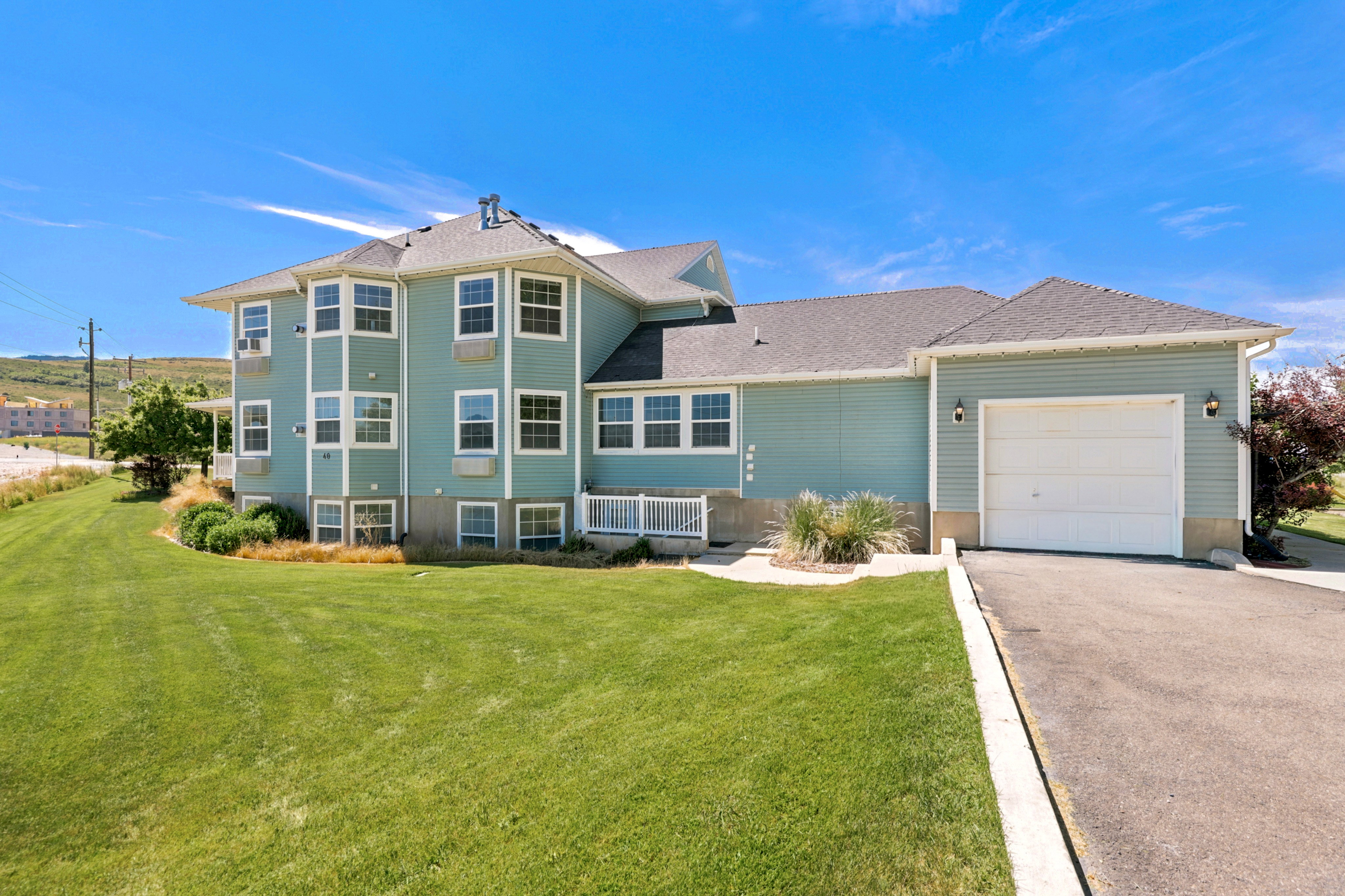 Contemporary multi-level residence featuring light blue siding and multiple bay windows