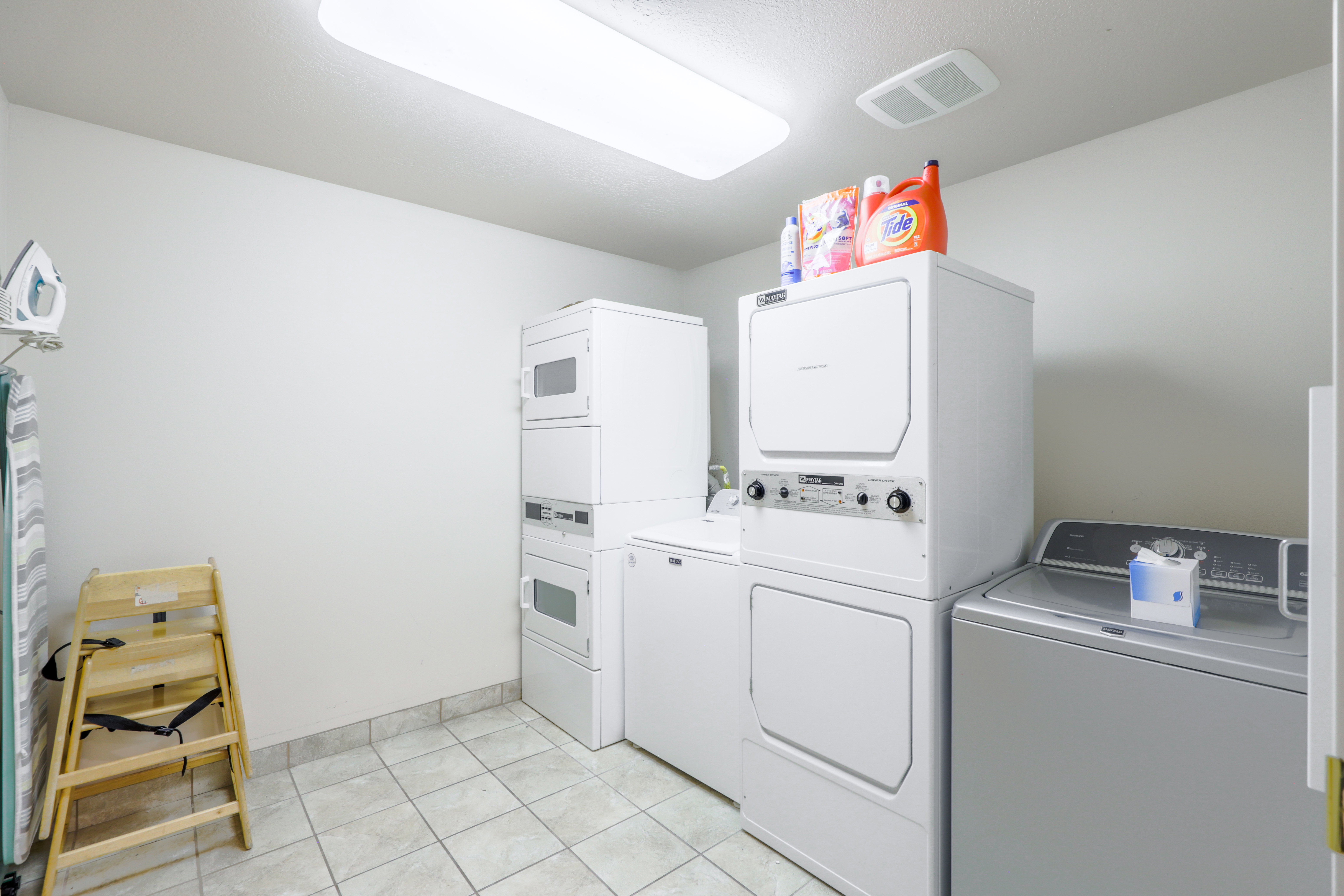 Dedicated laundry area featuring tile flooring, white walls, and a fluorescent ceiling light