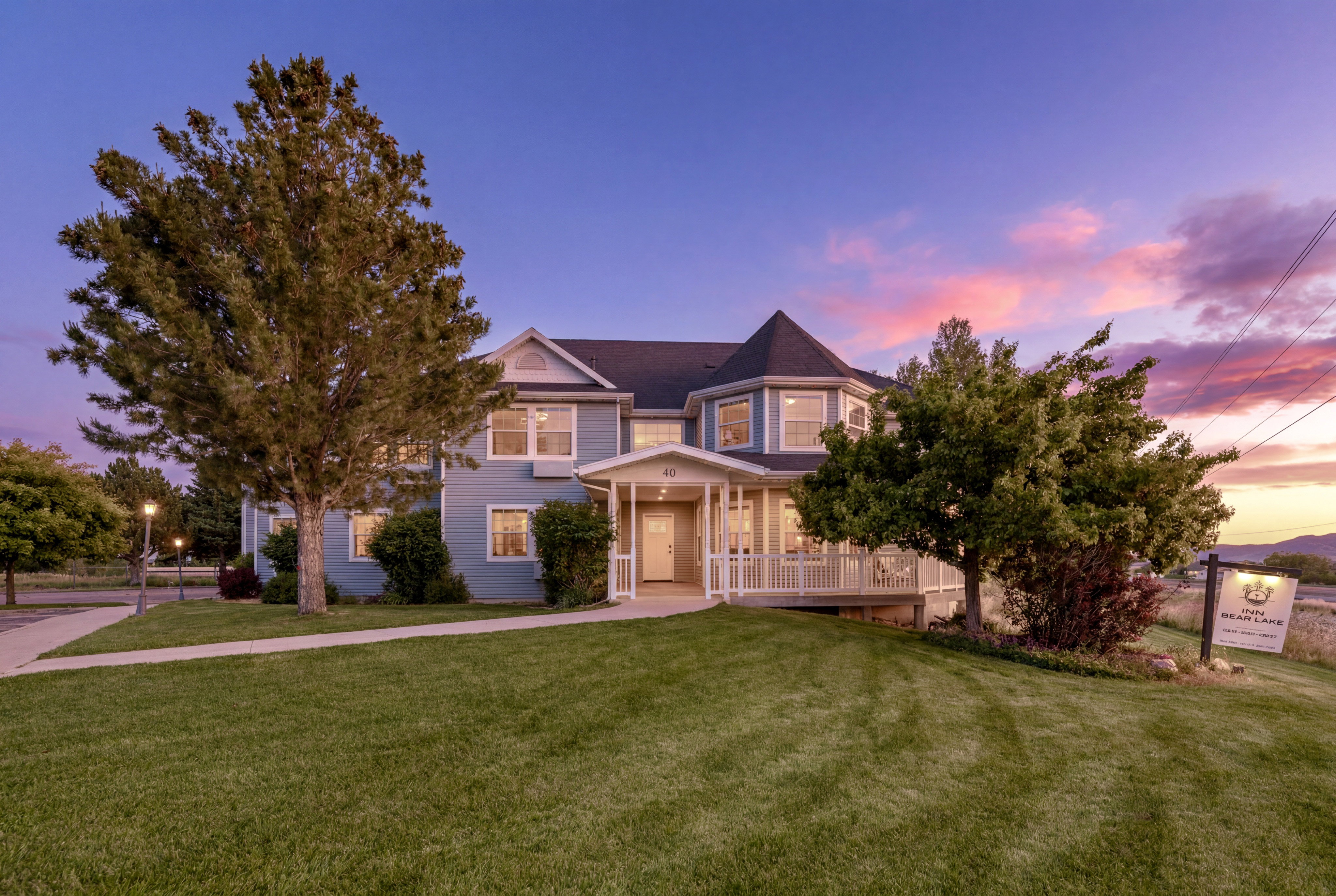 Light blue exterior with white trim, featuring a wrap-around porch and a turret-style architectural element
