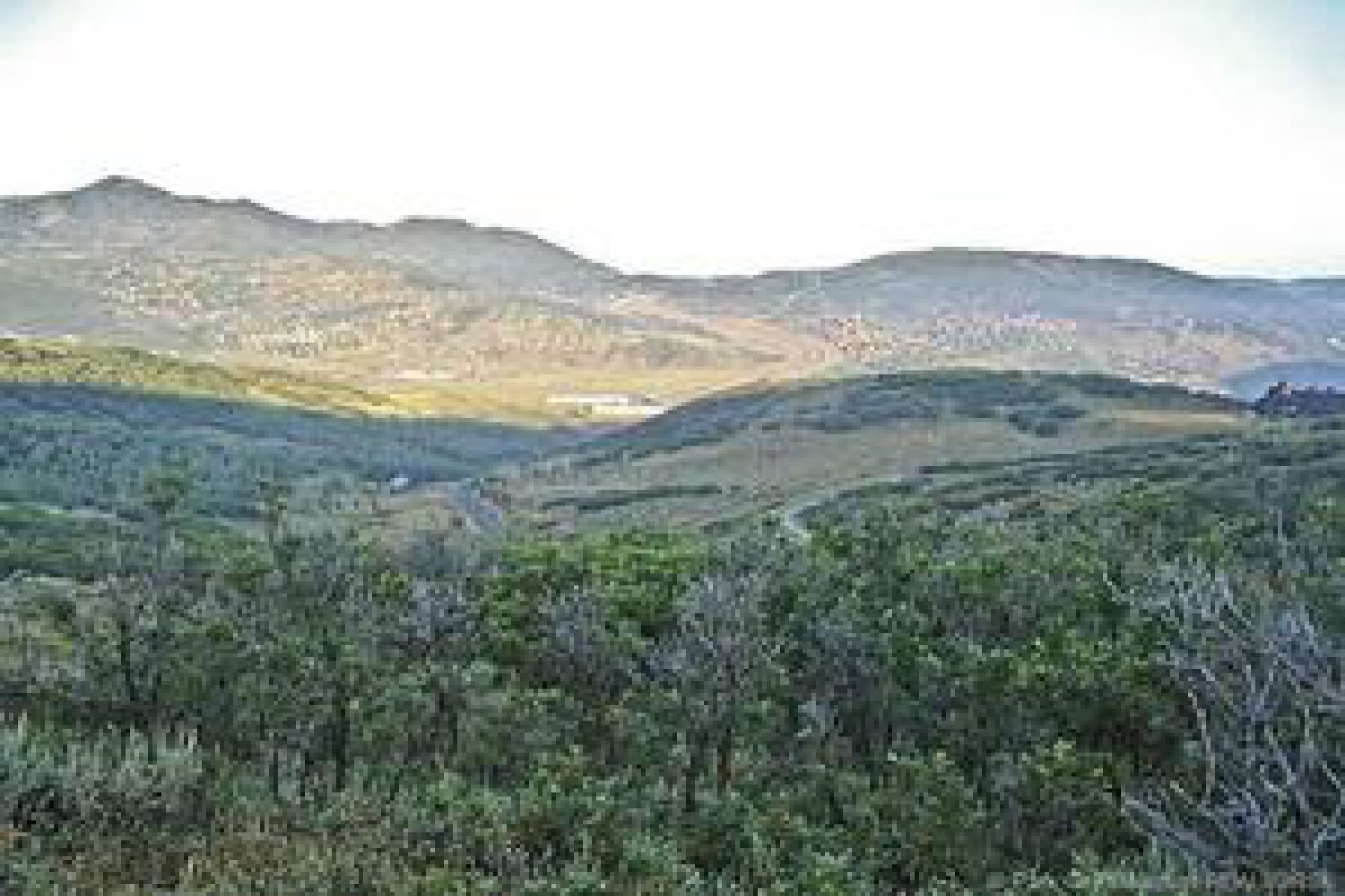 Expansive mountain landscape featuring varied terrain and distant structures