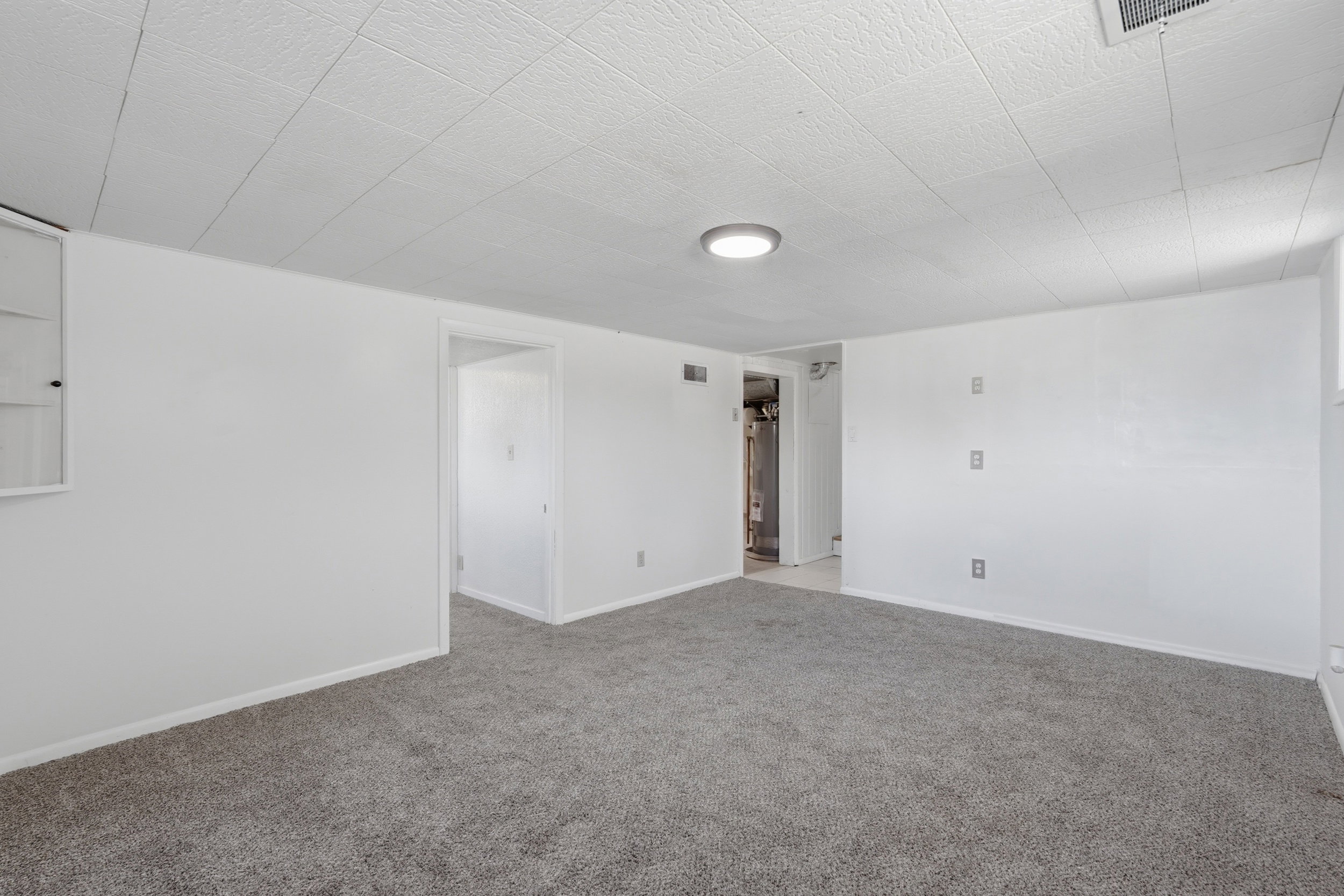 Carpeted interior space with white painted walls, white trim, and a drop ceiling