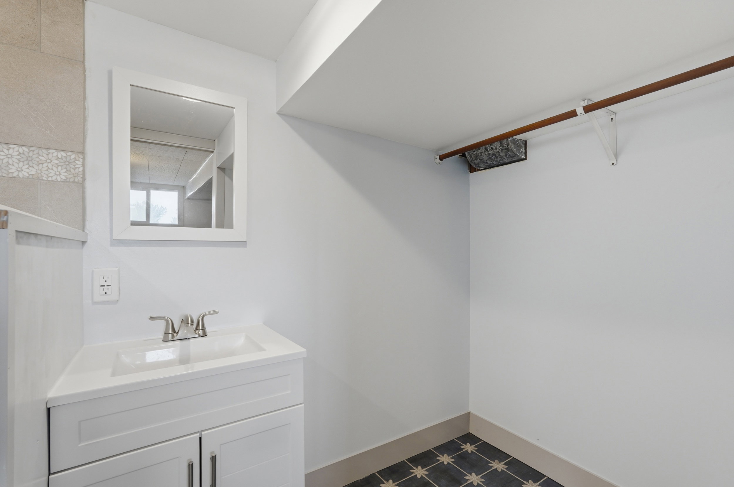 White vanity with integrated sink, brushed nickel faucet, and framed mirror