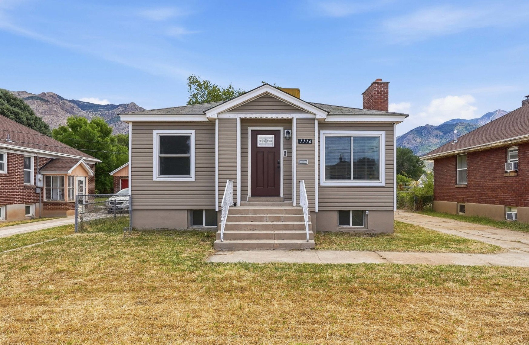 Exterior featuring light beige siding, a dark brown entry door, and white trim