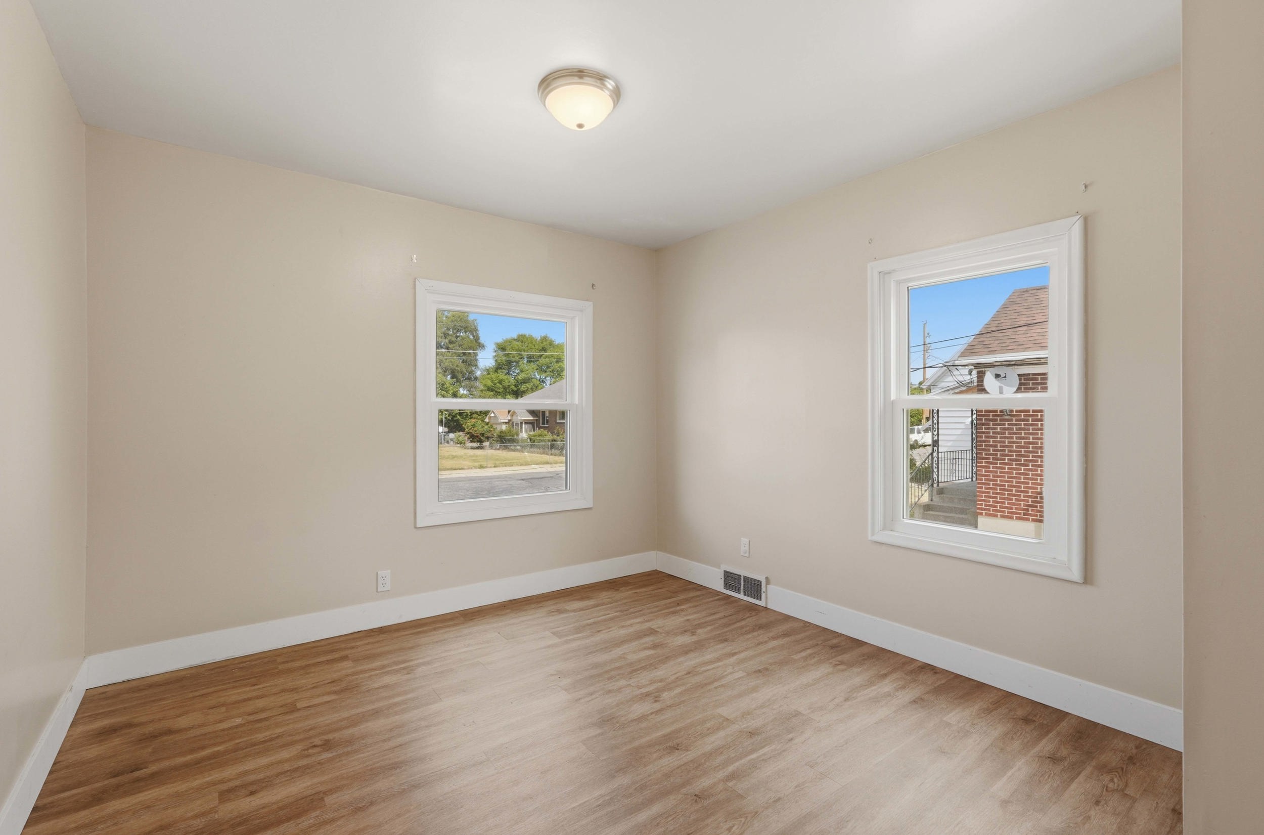 Neutral wall finishes, wood-finish flooring, white trim, and two windows