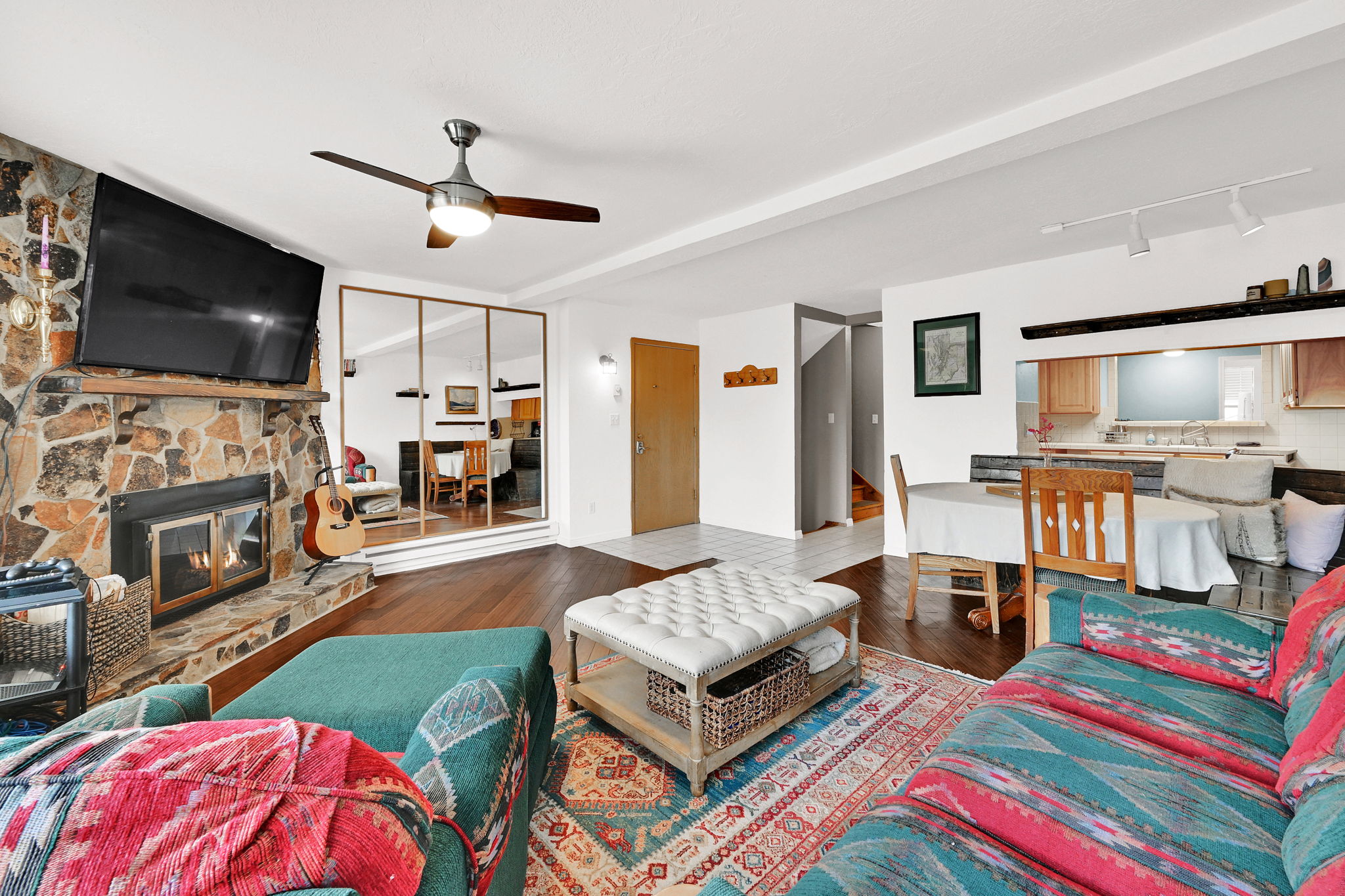 Living area featuring a stone-clad fireplace with hearth, wood-finish flooring, and a ceiling fan