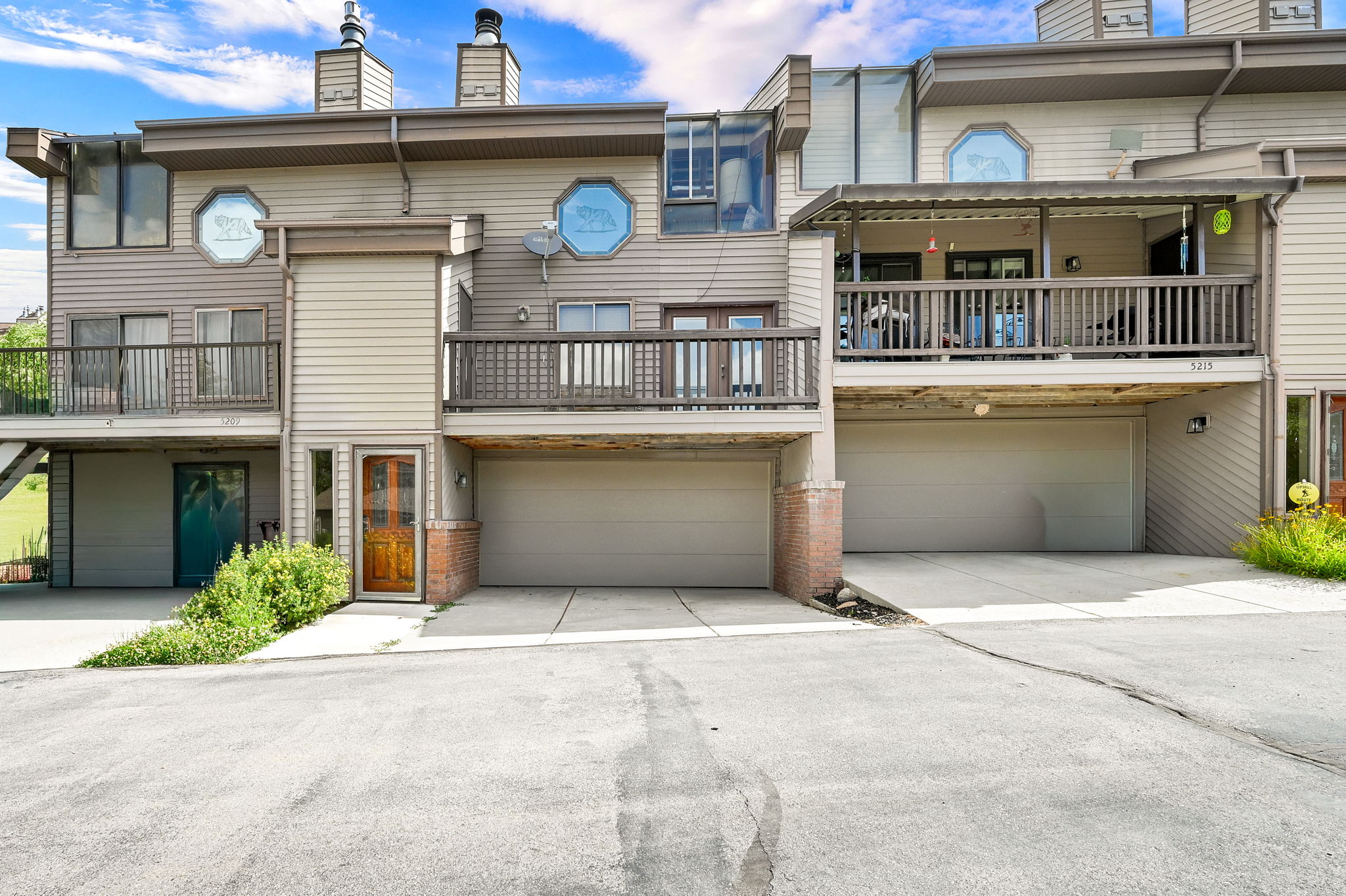 Multi-level townhome exterior featuring neutral siding, brown trim, and multiple balconies with dark wood railings