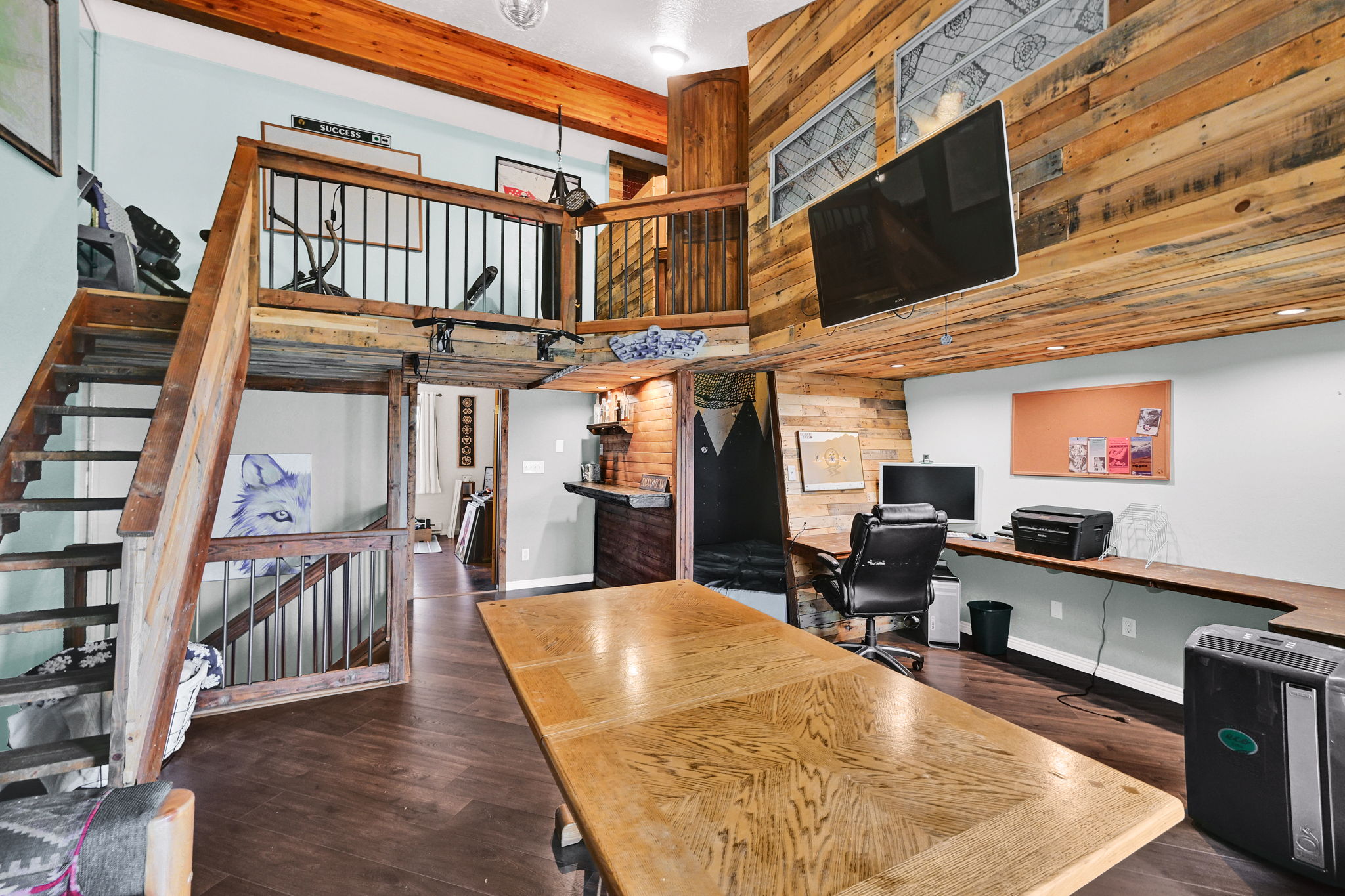 Multi-level interior featuring wood-finish flooring, exposed wooden ceiling beams, and a built-in wood desk