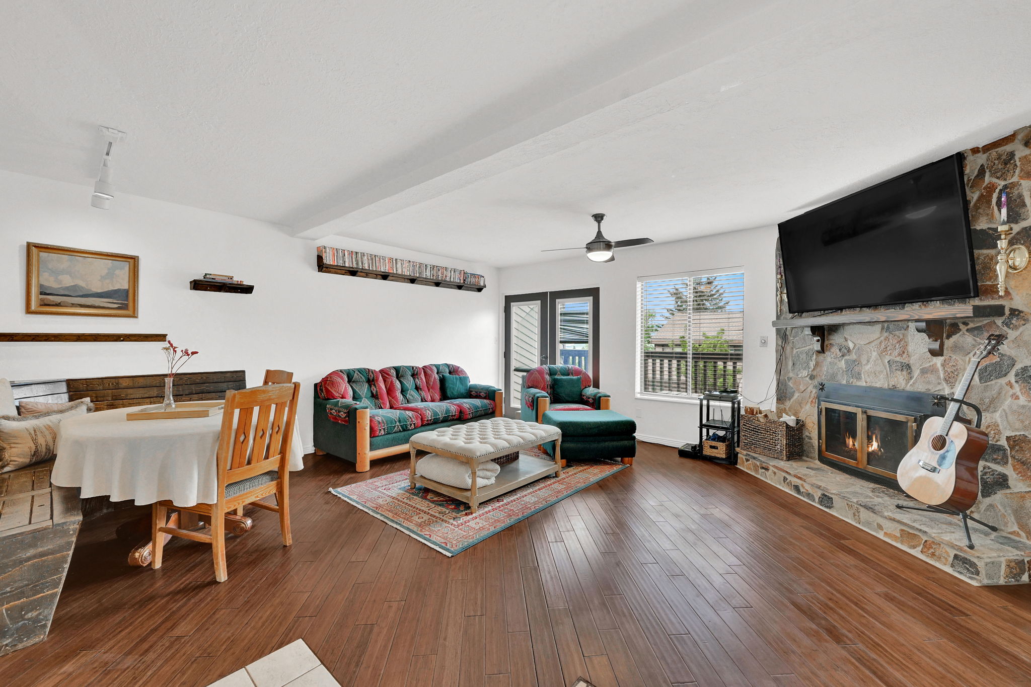 Spacious living area featuring wood-finish flooring, a stone fireplace with a raised hearth, and a built-in stone bench