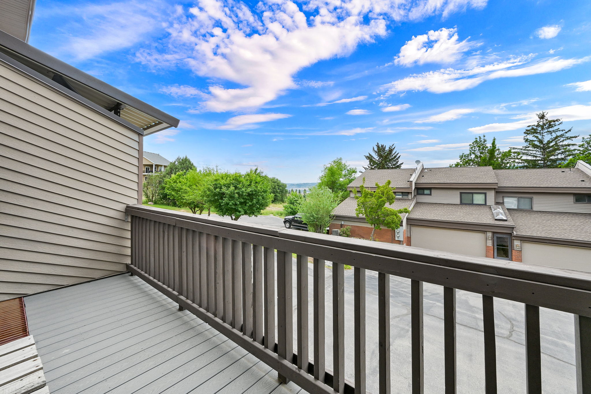 Private balcony featuring composite decking, wood railing, and horizontal siding