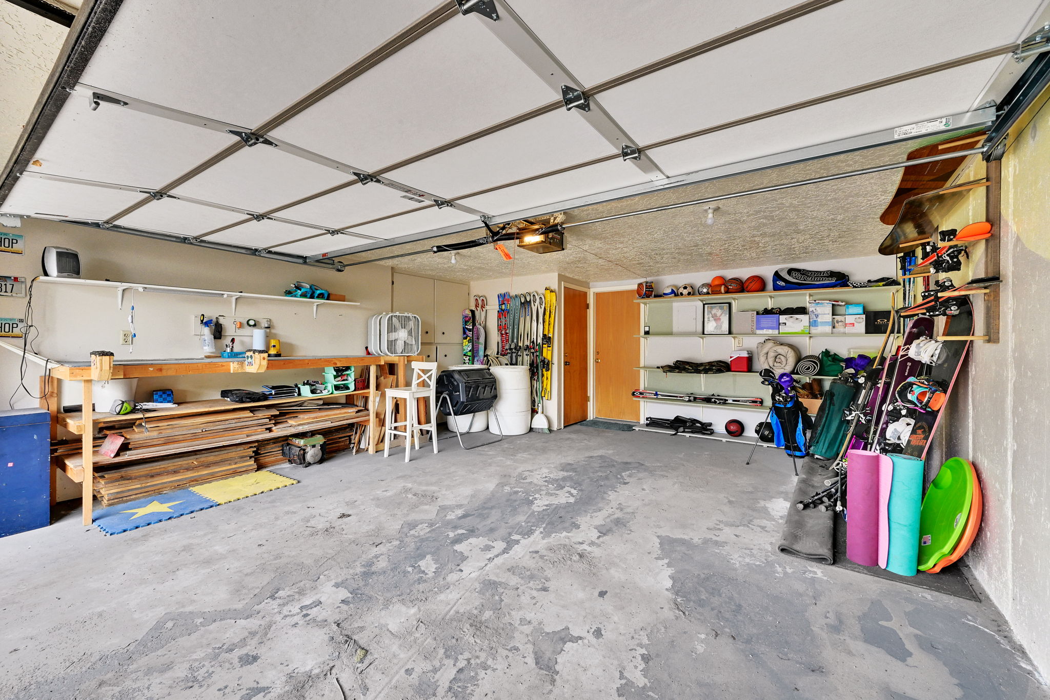 Spacious garage featuring a concrete floor, built-in shelving, a workbench, and a rear access door