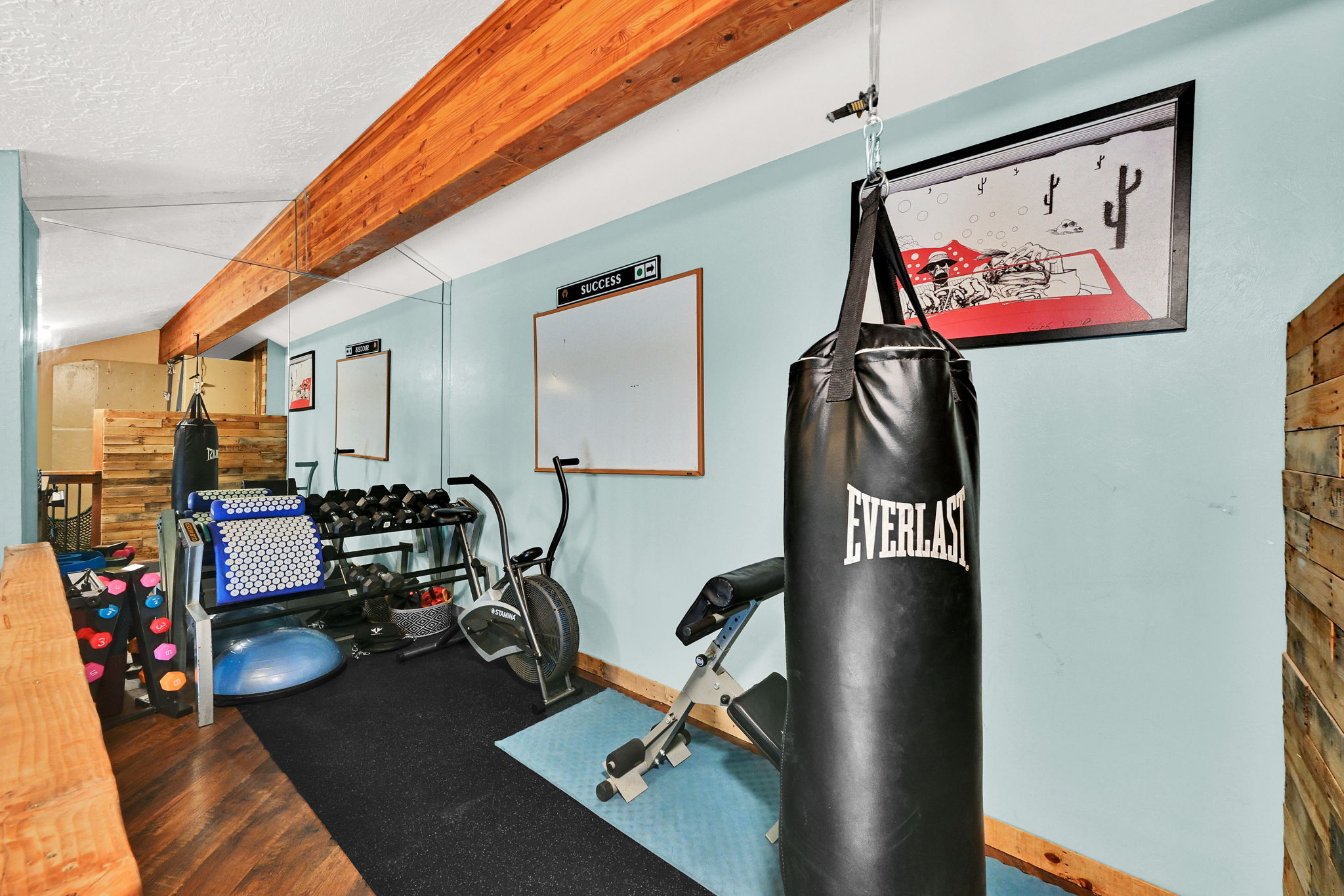 Dedicated fitness area featuring wood-finish flooring and exposed timber beams