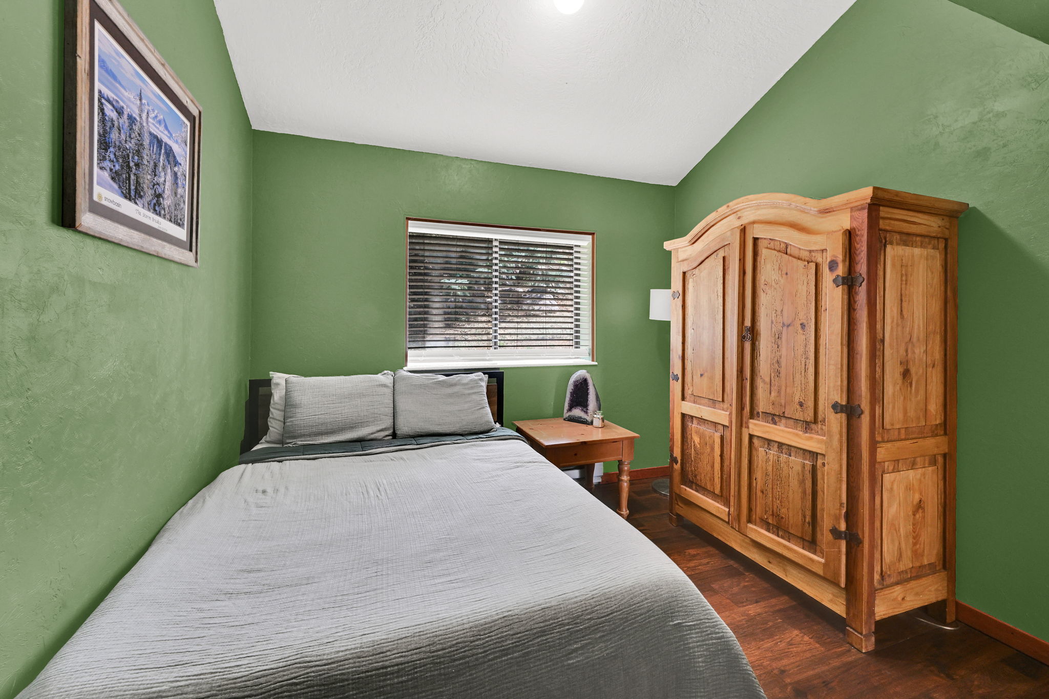 Bedroom featuring a window with horizontal blinds, wood-finish flooring, and green painted walls
