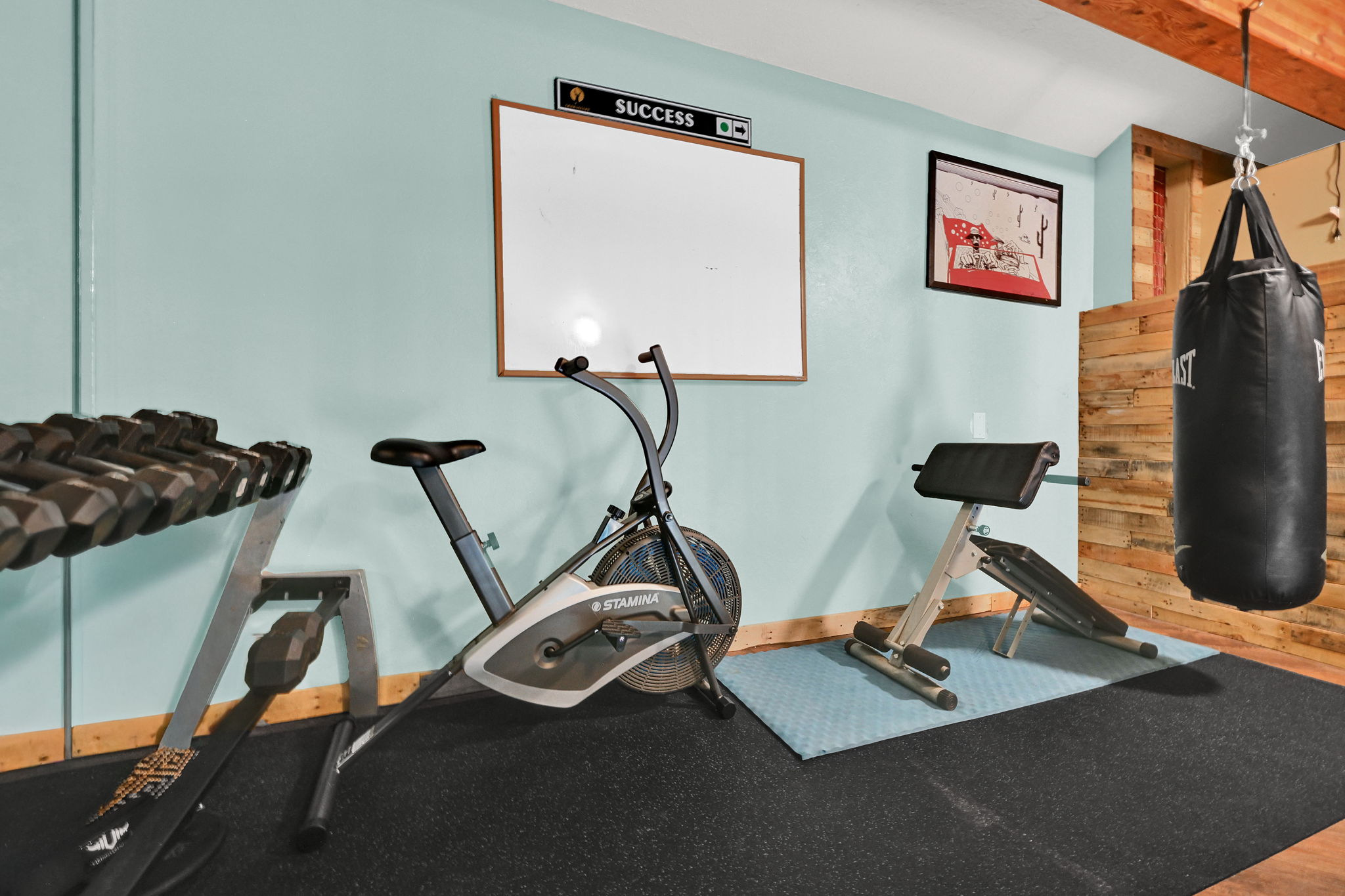 Finished basement space featuring light blue walls, exposed wood ceiling joists, and a wood-paneled accent wall