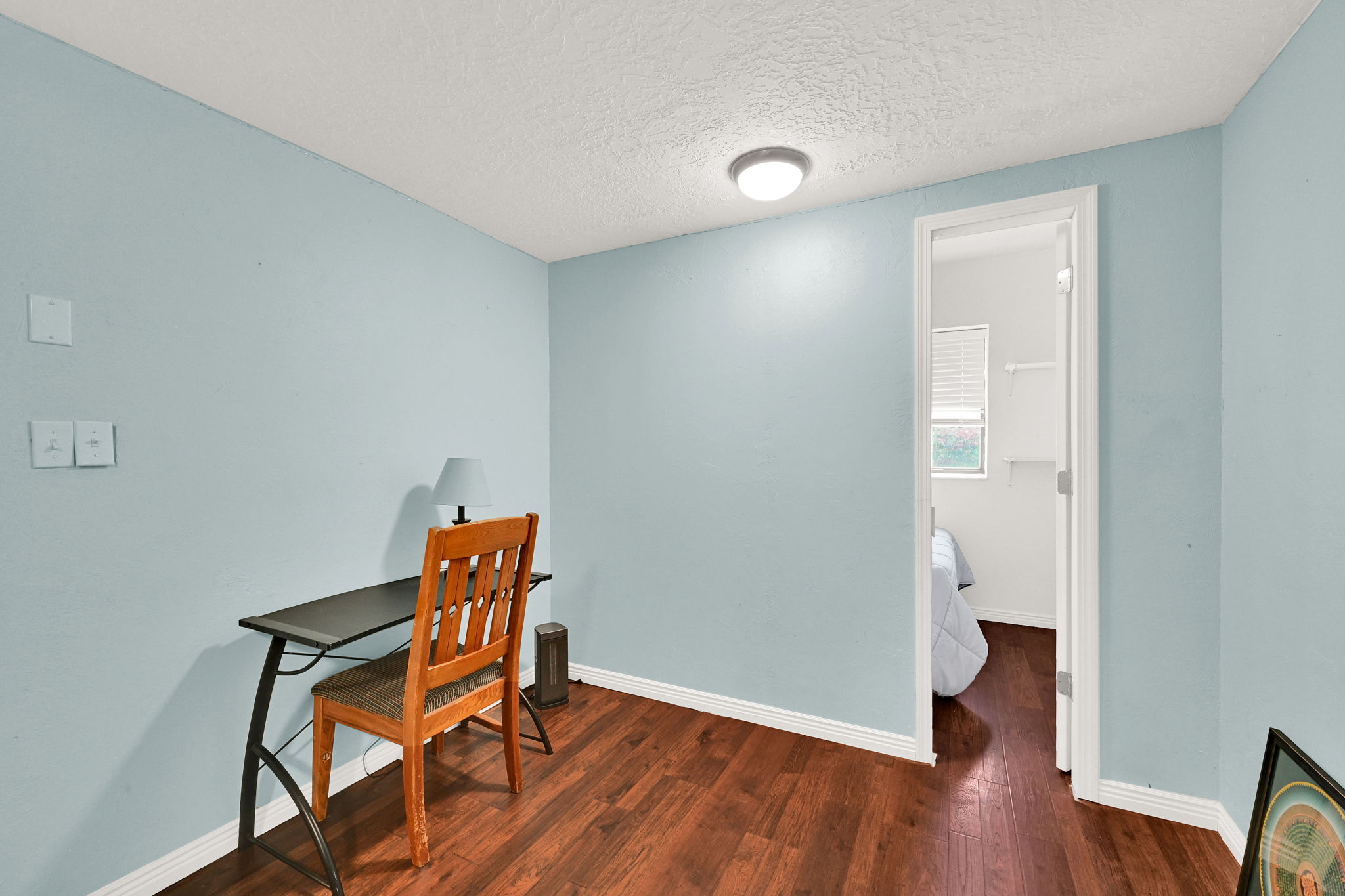 Room featuring wood-finish flooring, light blue walls, and white trim