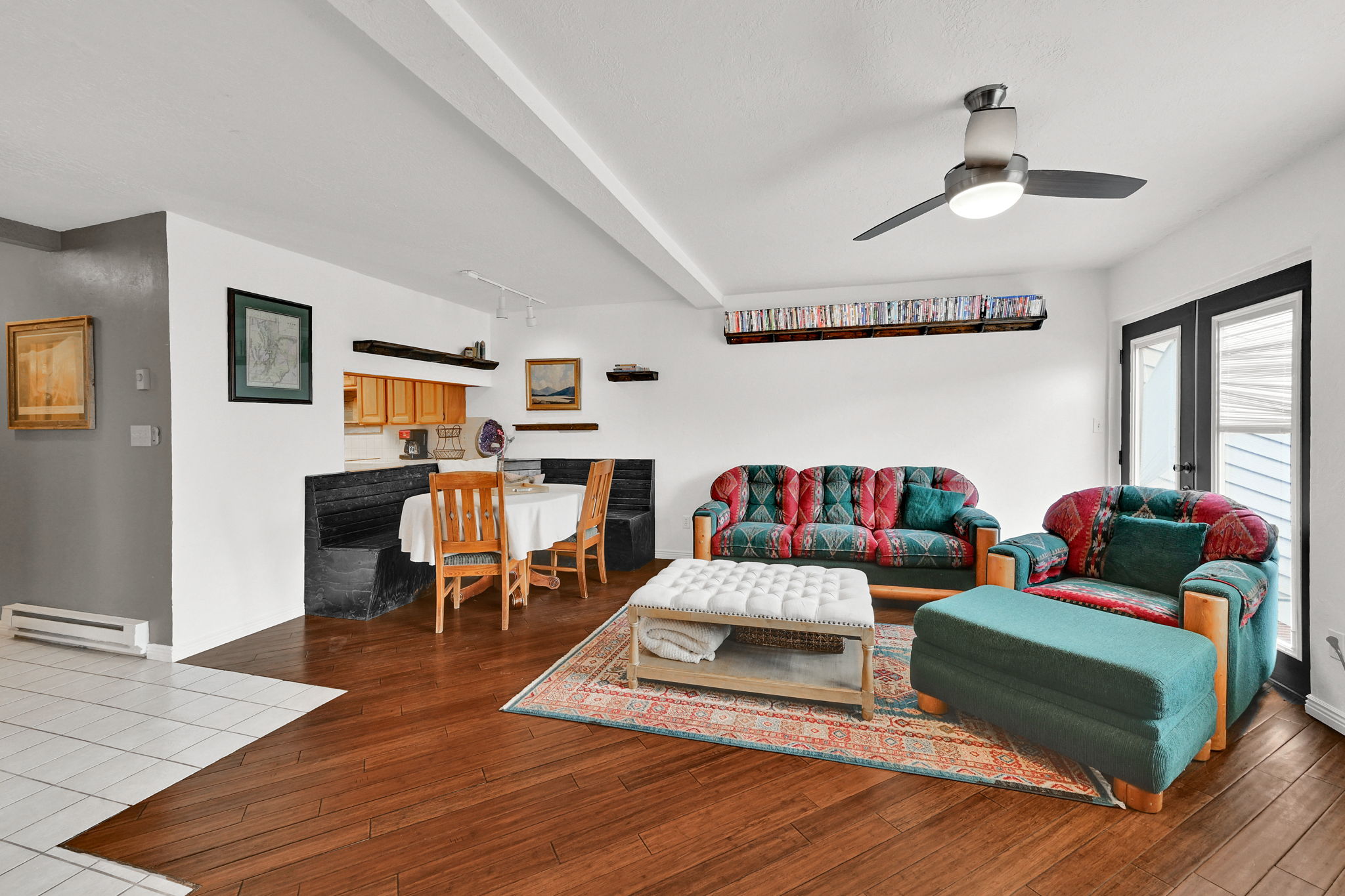 Open-concept living space featuring wood-finish flooring, a built-in dining nook, and a ceiling fan with integrated lighting