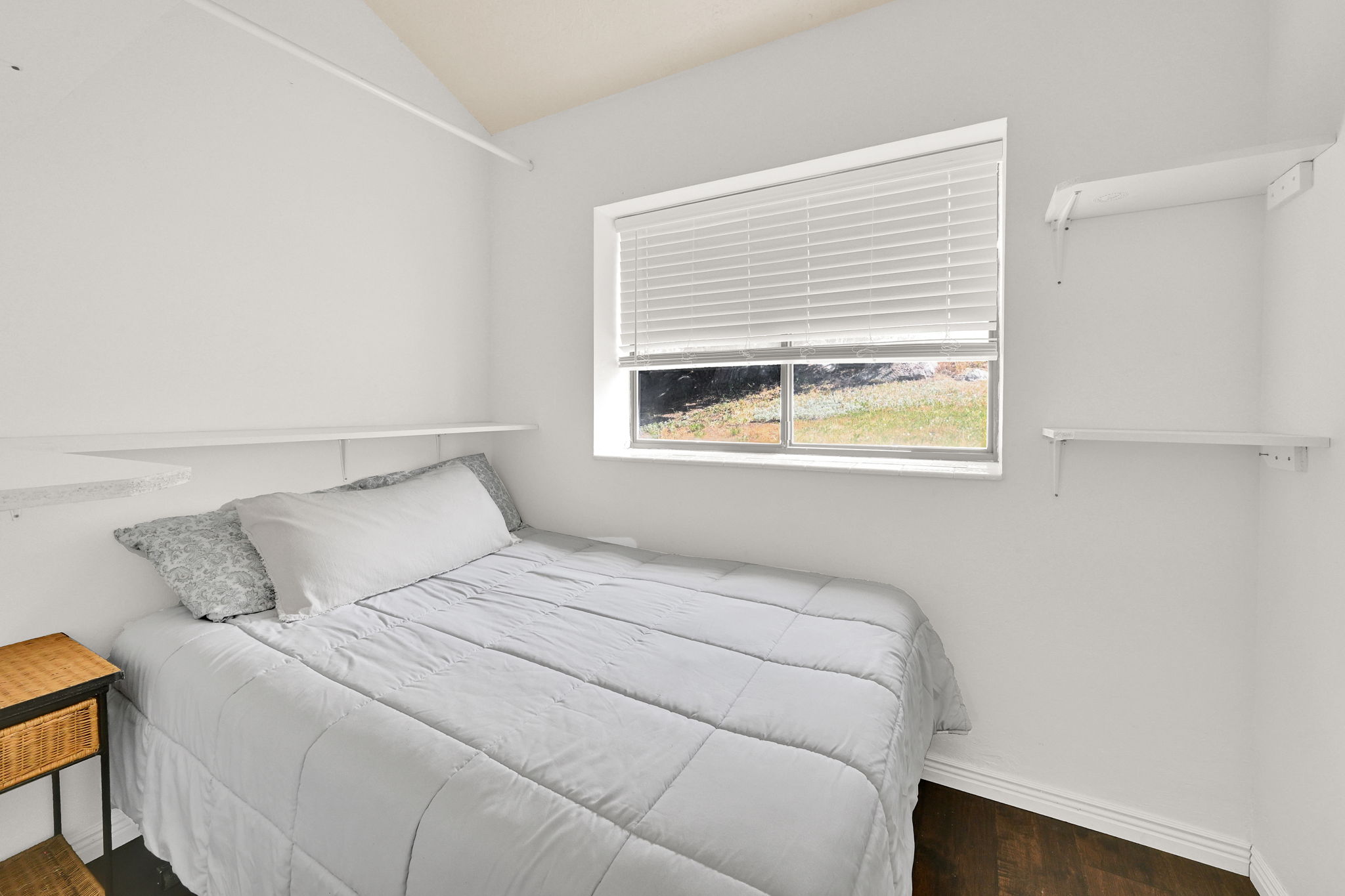Bright room featuring dark wood-finish flooring and a window with blinds