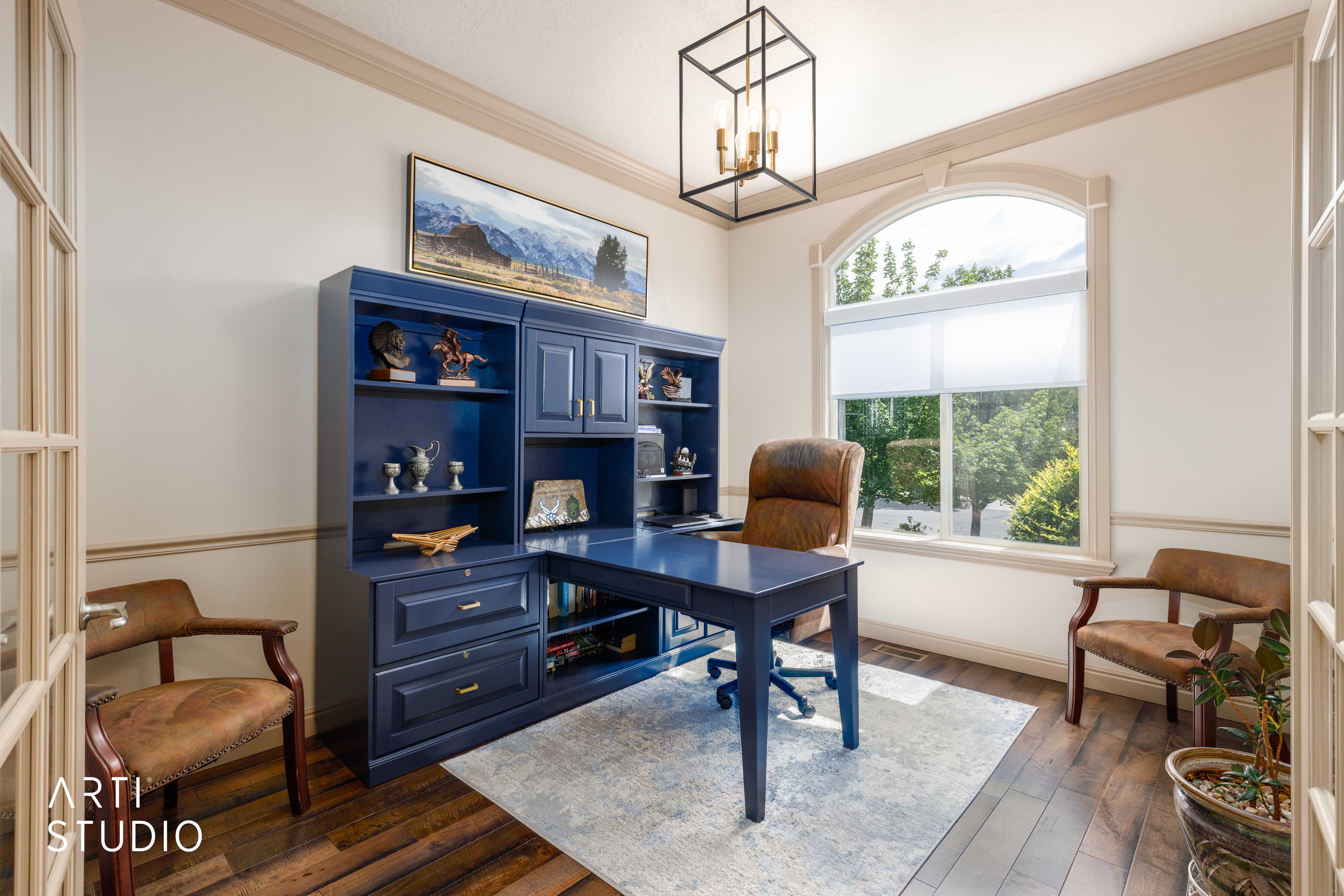 Main level office with wood flooring, a large arched window, and french doors