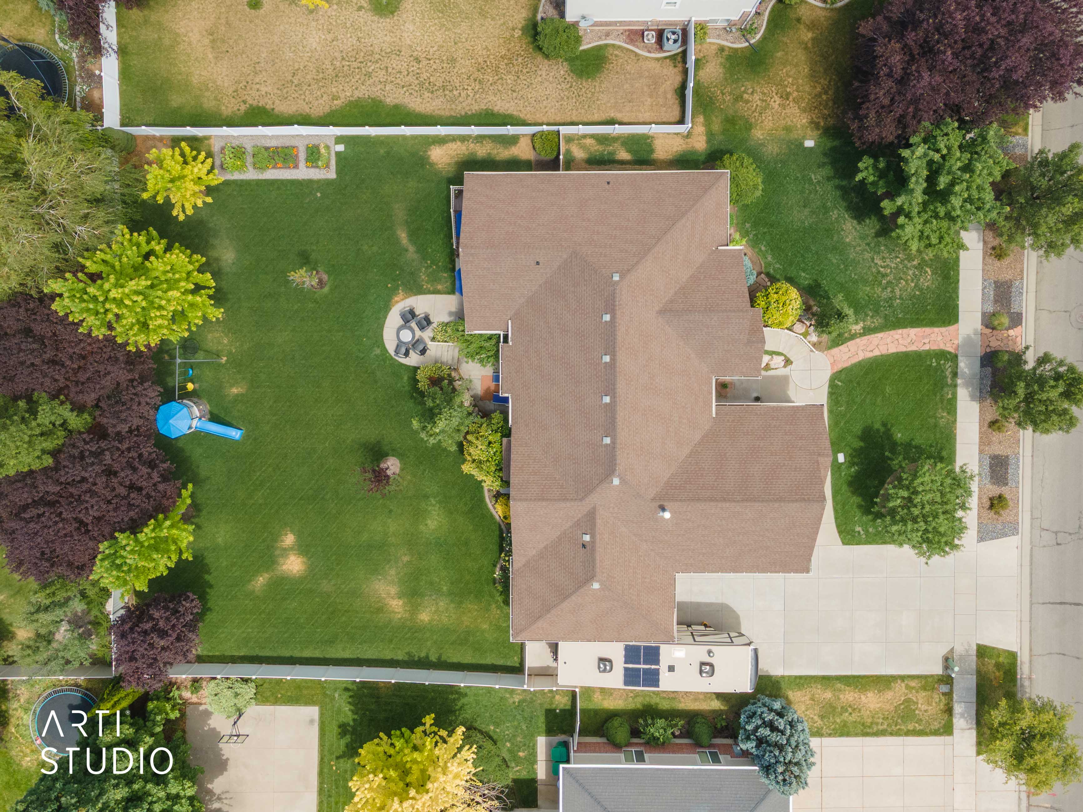 Expansive property featuring a multi-gabled roofline, a large paved driveway, and a spacious backyard with a dedicated patio area