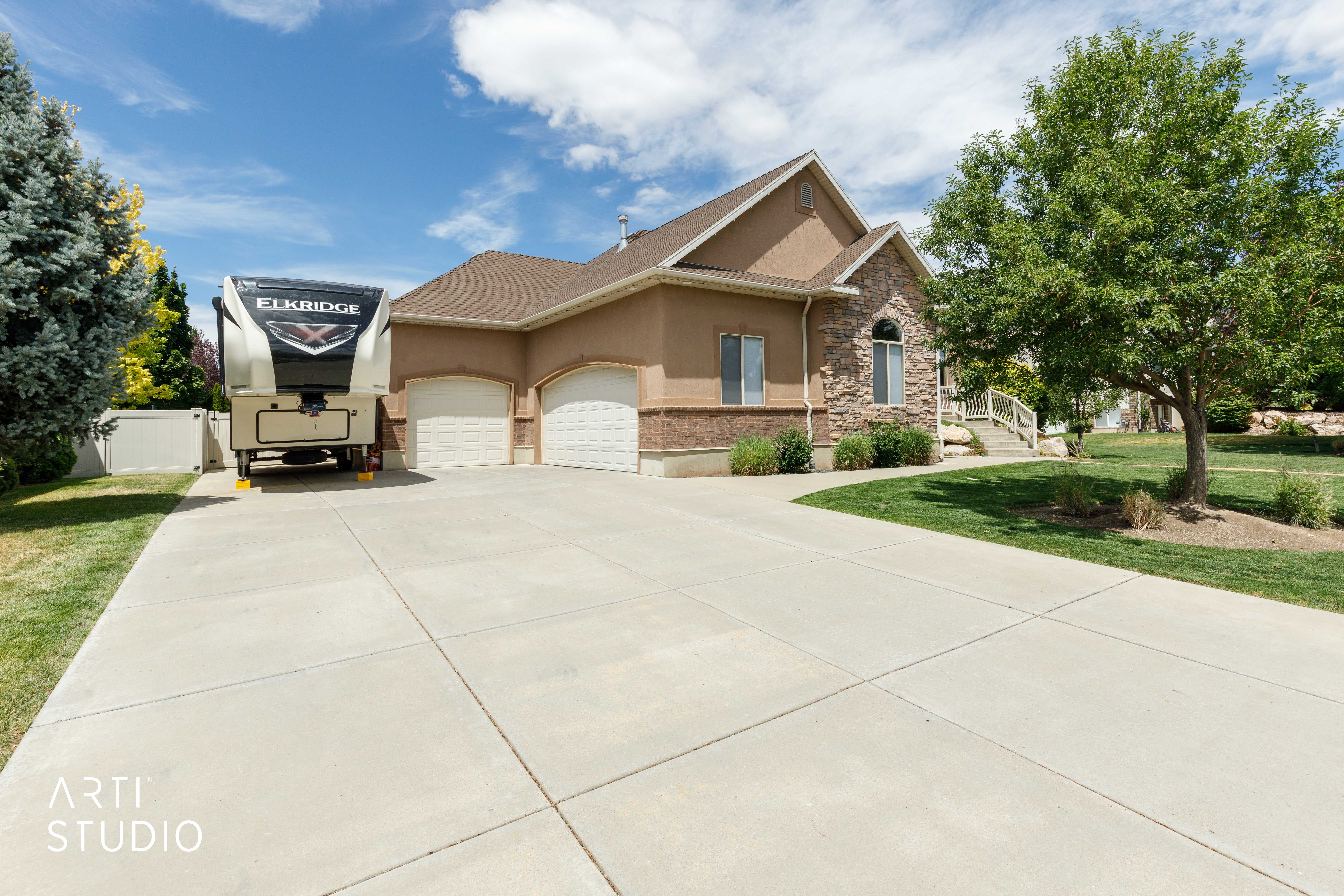 spacious three-car garage, an extended concrete driveway, and dedicated RV parking complete with a large RV pad.
