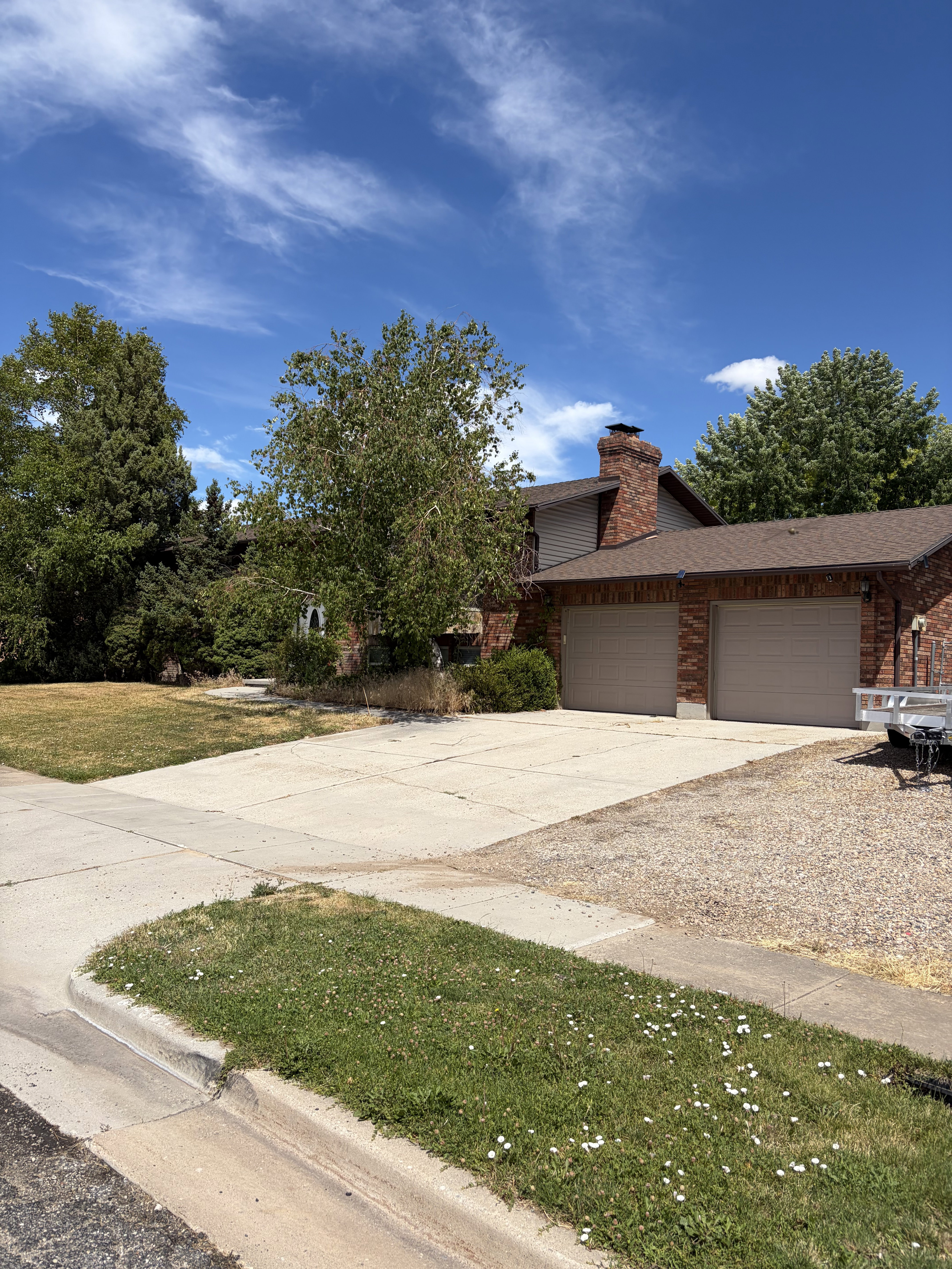 Brick exterior with a prominent chimney, a two-car garage, and a concrete driveway