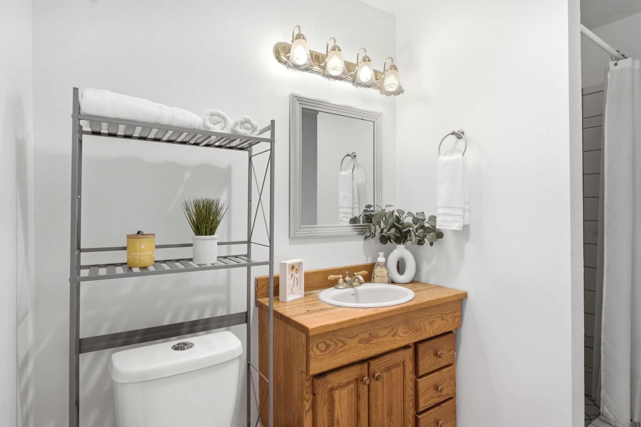 Bathroom featuring a wood-finish vanity with an integrated sink, polished brass-finish faucet, and coordinating framed mirror