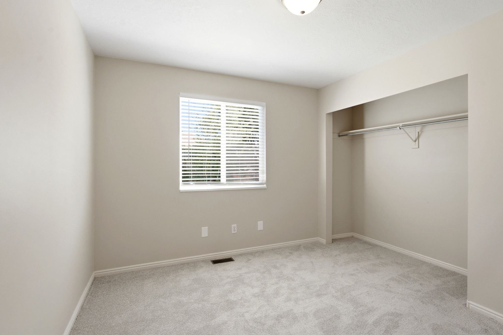 Bedroom featuring neutral wall paint, light gray carpeting, and a window with blinds