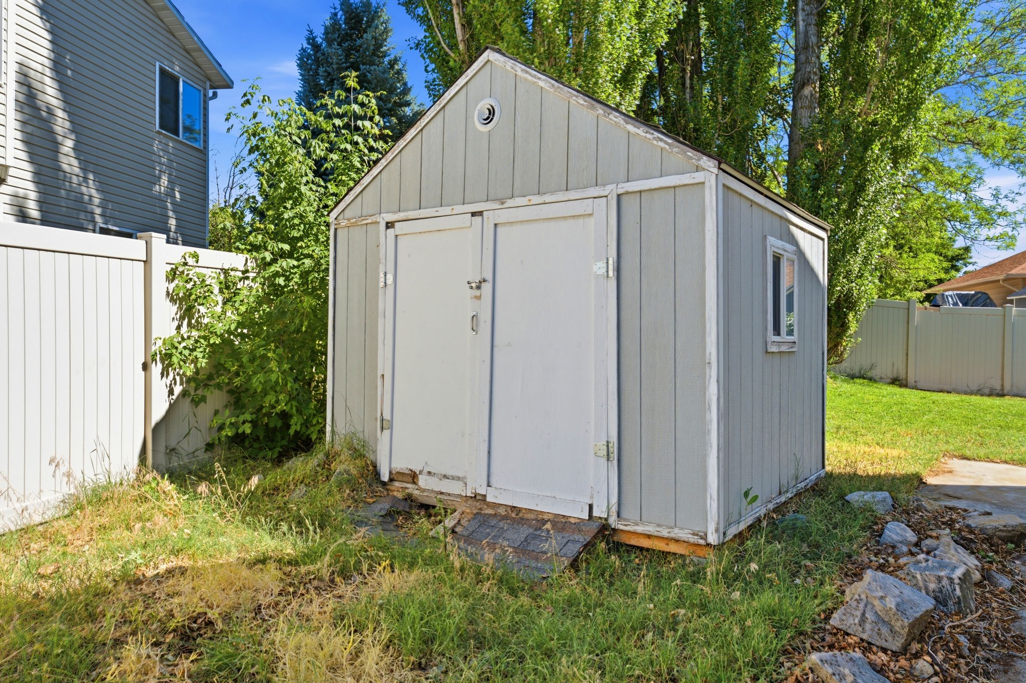Detached shed featuring a gabled roof, double entry doors, a side window, and vertical siding