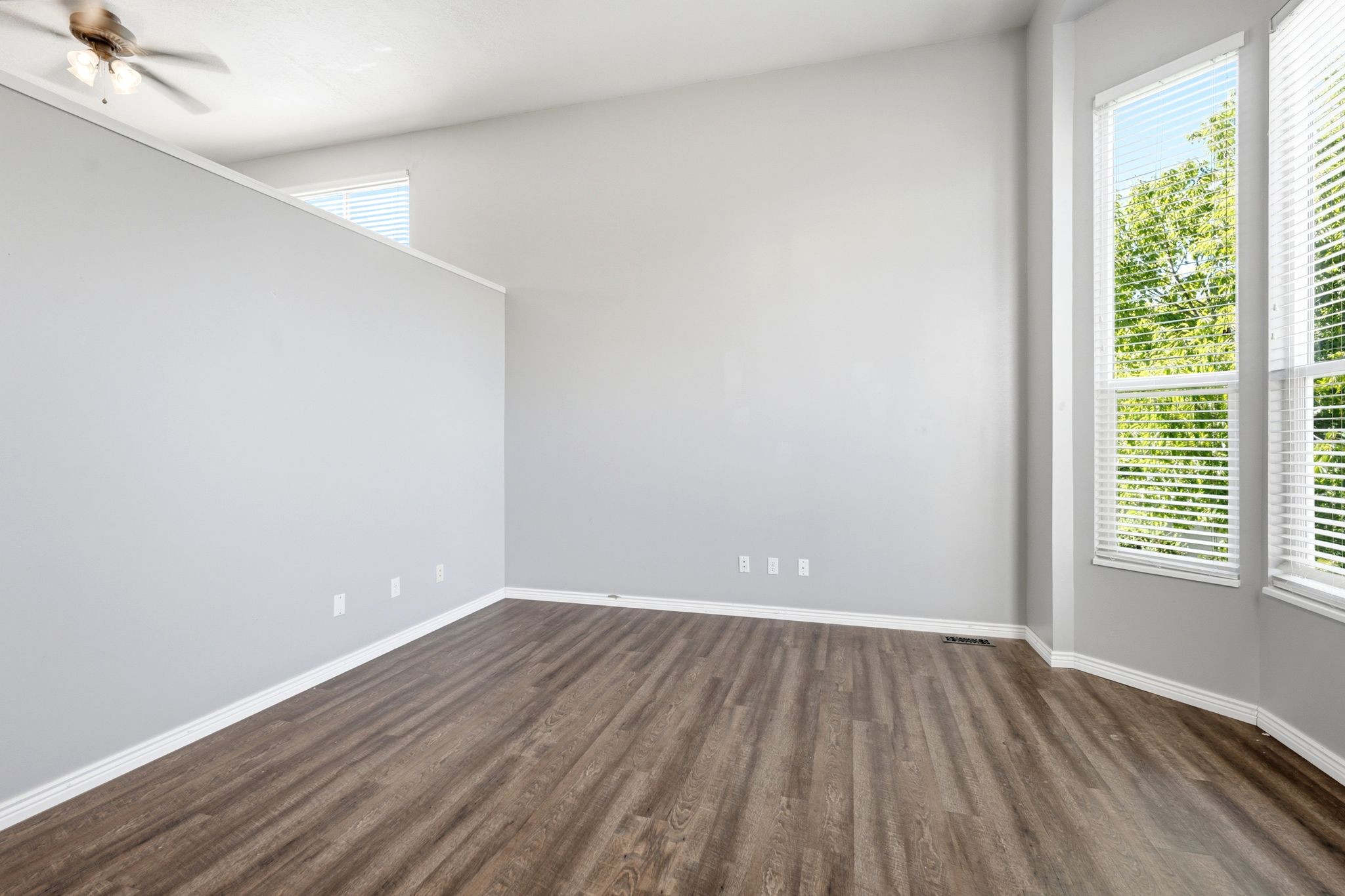Spacious room featuring wood-finish flooring, light grey walls, and white baseboards