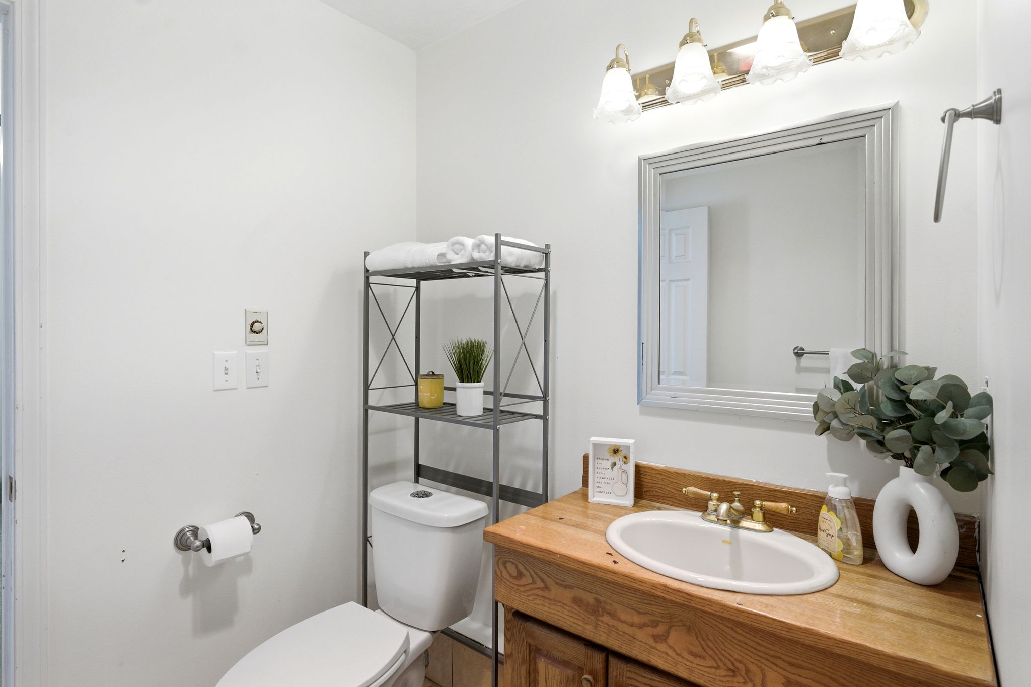Vanity with a wood-finish countertop, oval undermount sink, and brass-tone faucet