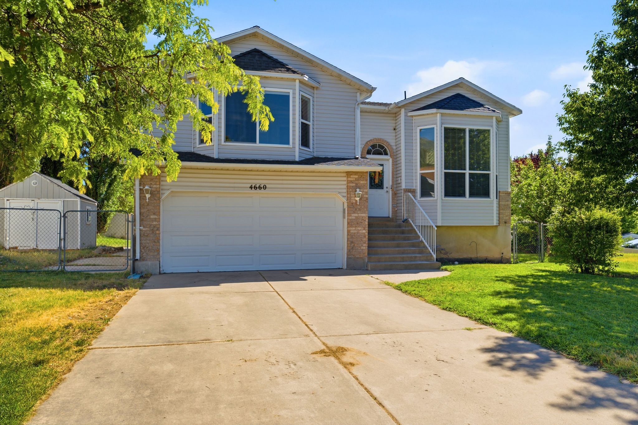 Two-story residence featuring light-colored siding, a two-car garage, and a concrete driveway