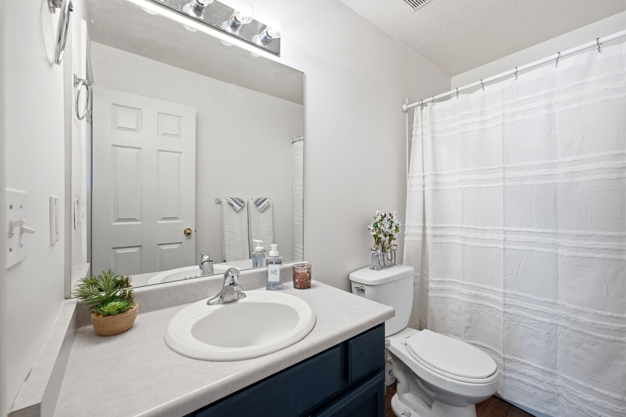 Bathroom featuring a vanity with a white oval sink, chrome faucet, and dark blue cabinetry