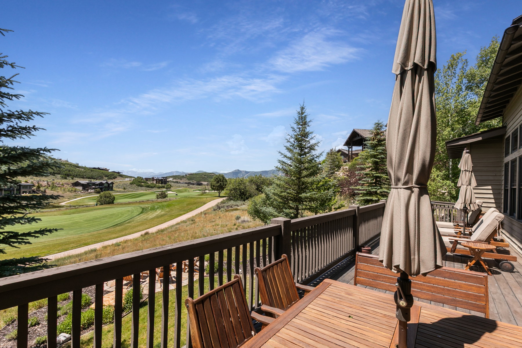 Expansive wooden deck with a slatted railing overlooking a golf course and distant hills