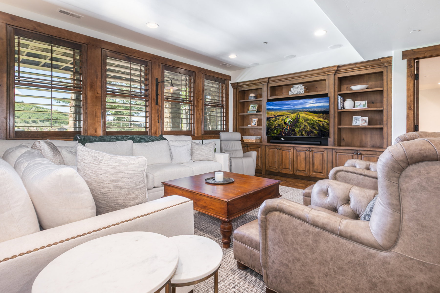 Living area featuring a built-in entertainment center with shelving and storage cabinetry, wood-finish window frames, recessed lighting, and a textured area rug