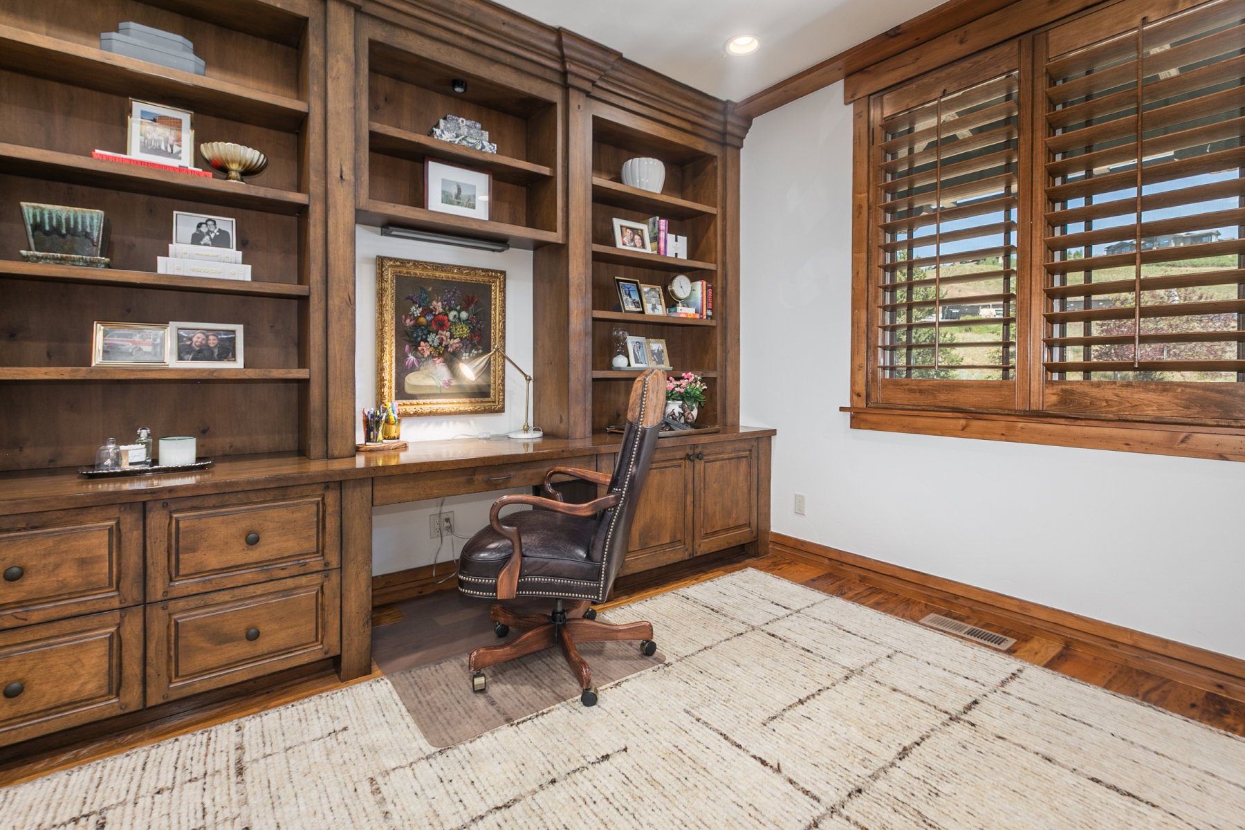 Integrated wood-finish shelving and desk area with extensive built-in storage