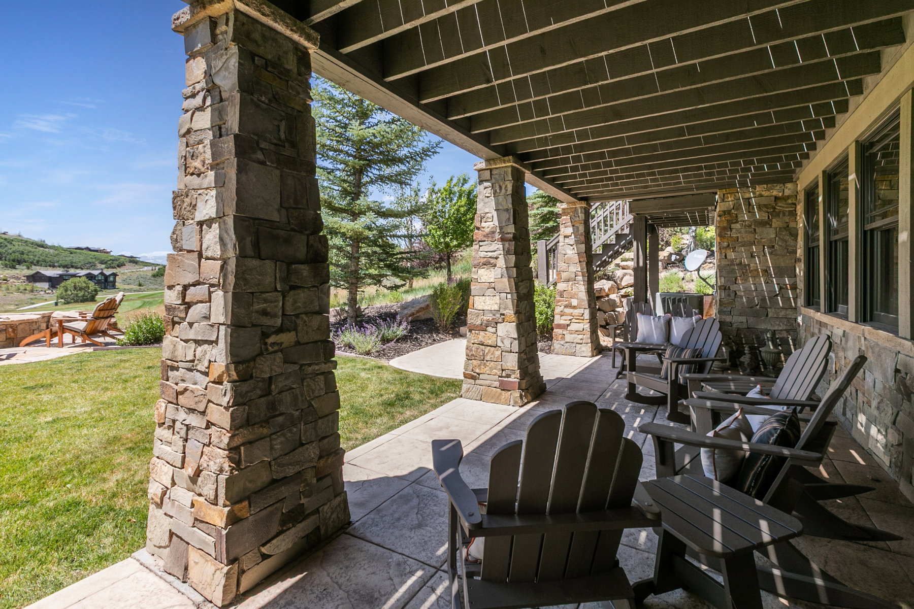 Covered patio with stamped concrete flooring, supported by stone pillars