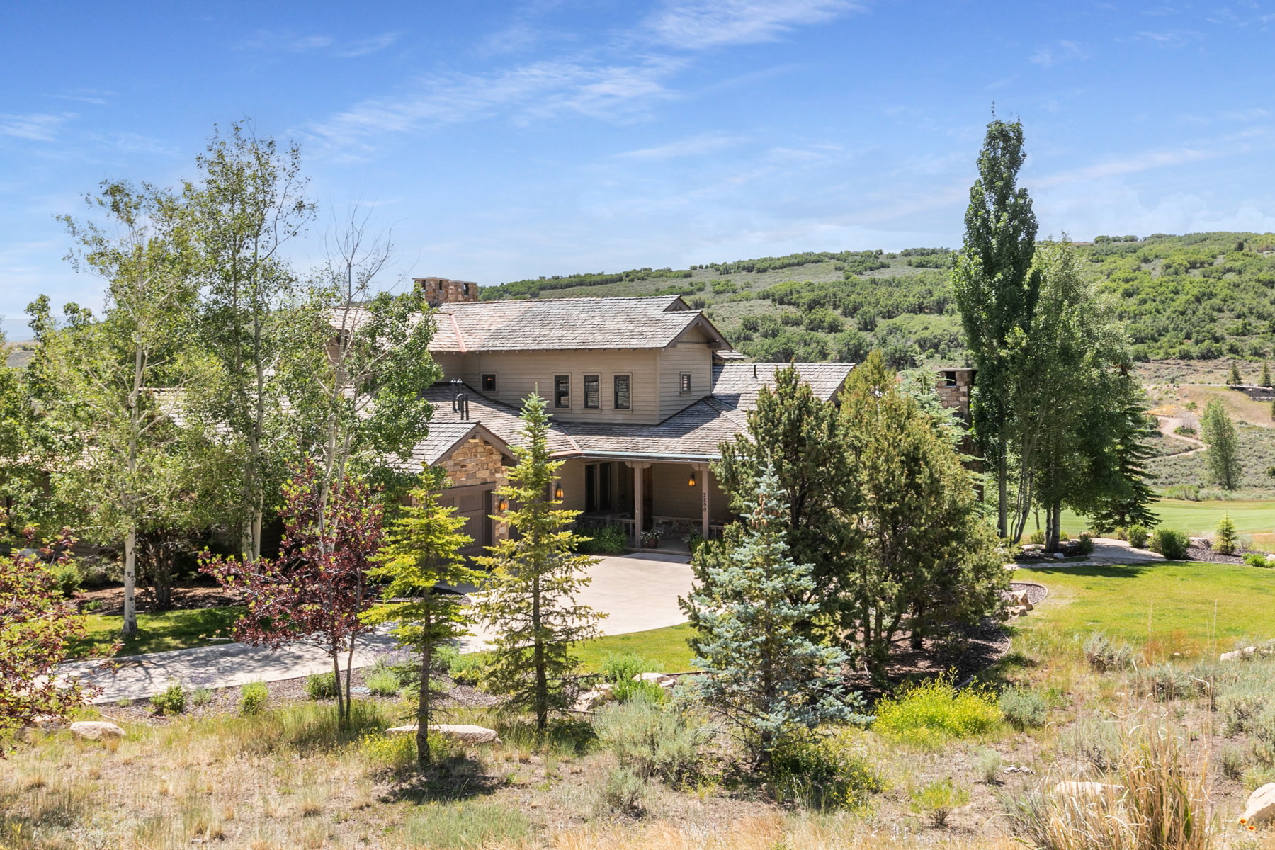 Expansive property featuring a stone and siding exterior, a multi-car driveway, and a covered entryway