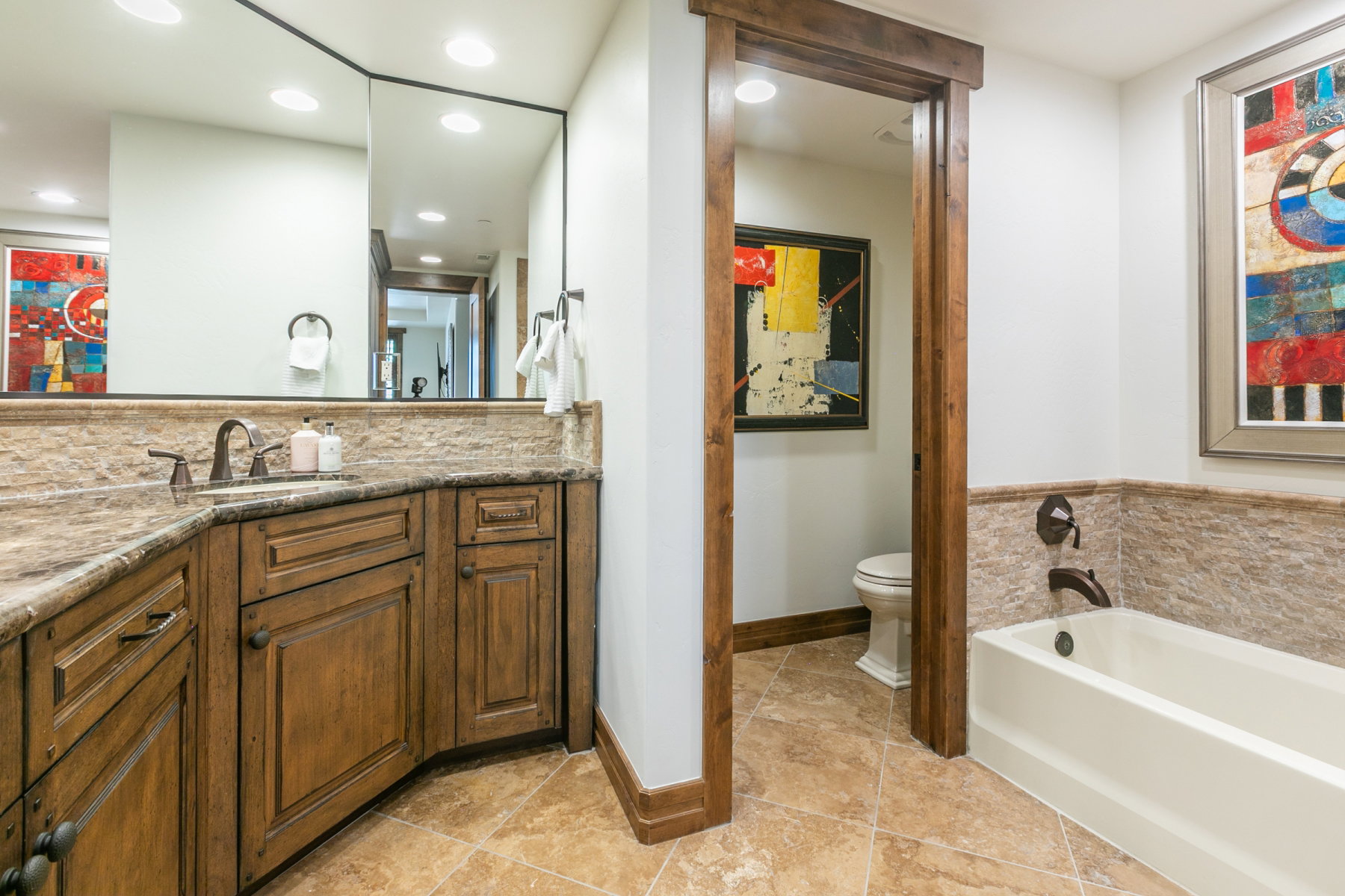 Bathroom featuring a corner vanity with a stone countertop, an undermount sink, and dark bronze fixtures