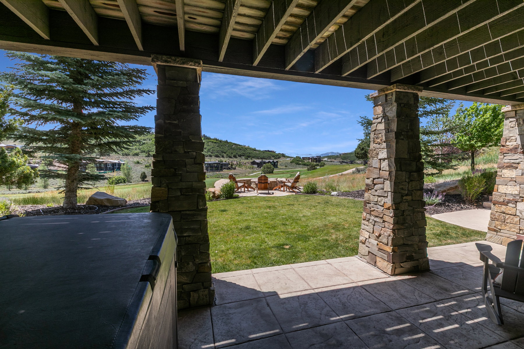 Covered patio area featuring stamped concrete flooring and stone-clad support columns