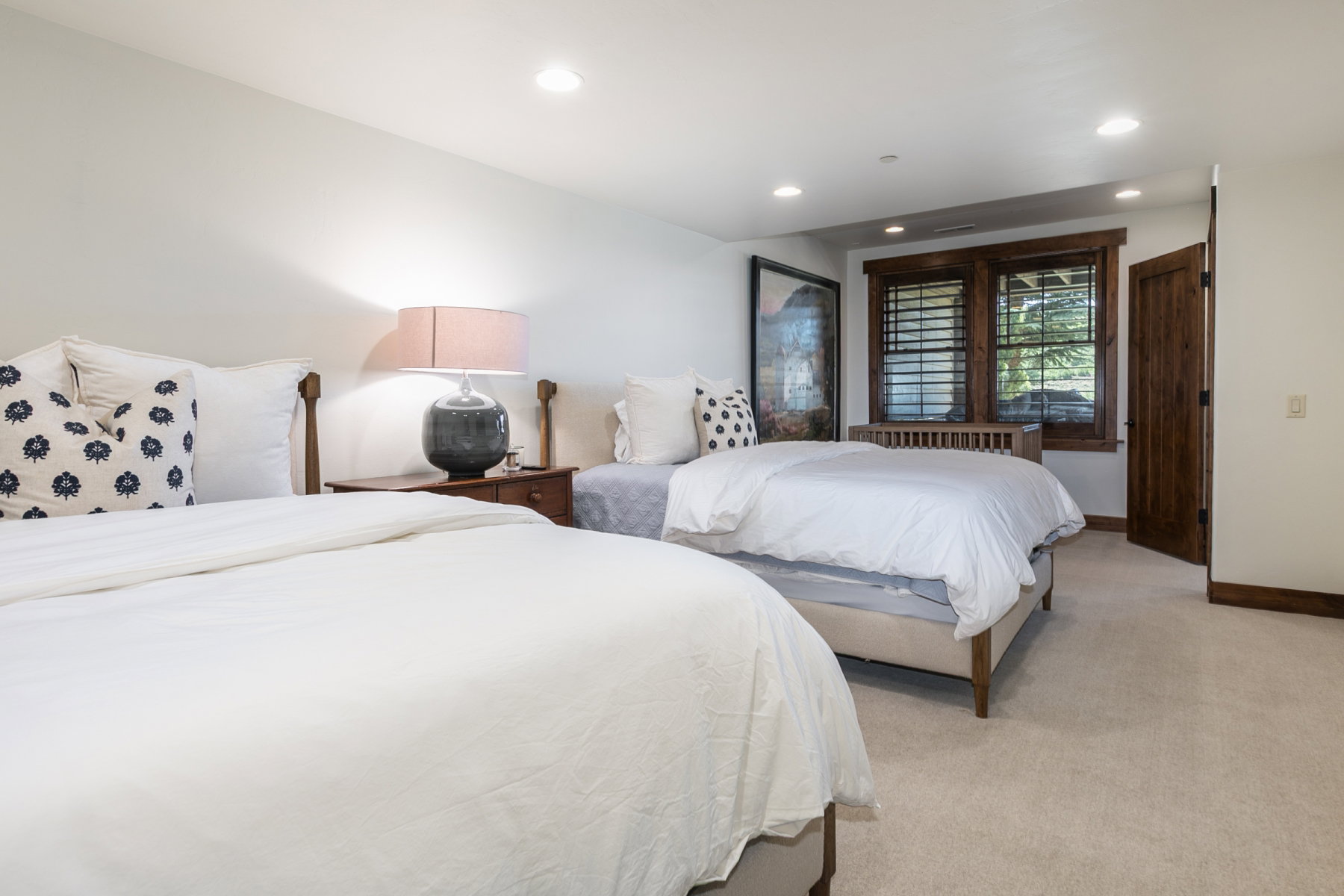 Carpeted room featuring recessed lighting, a window with wood shutters, wood trim, and a wood door