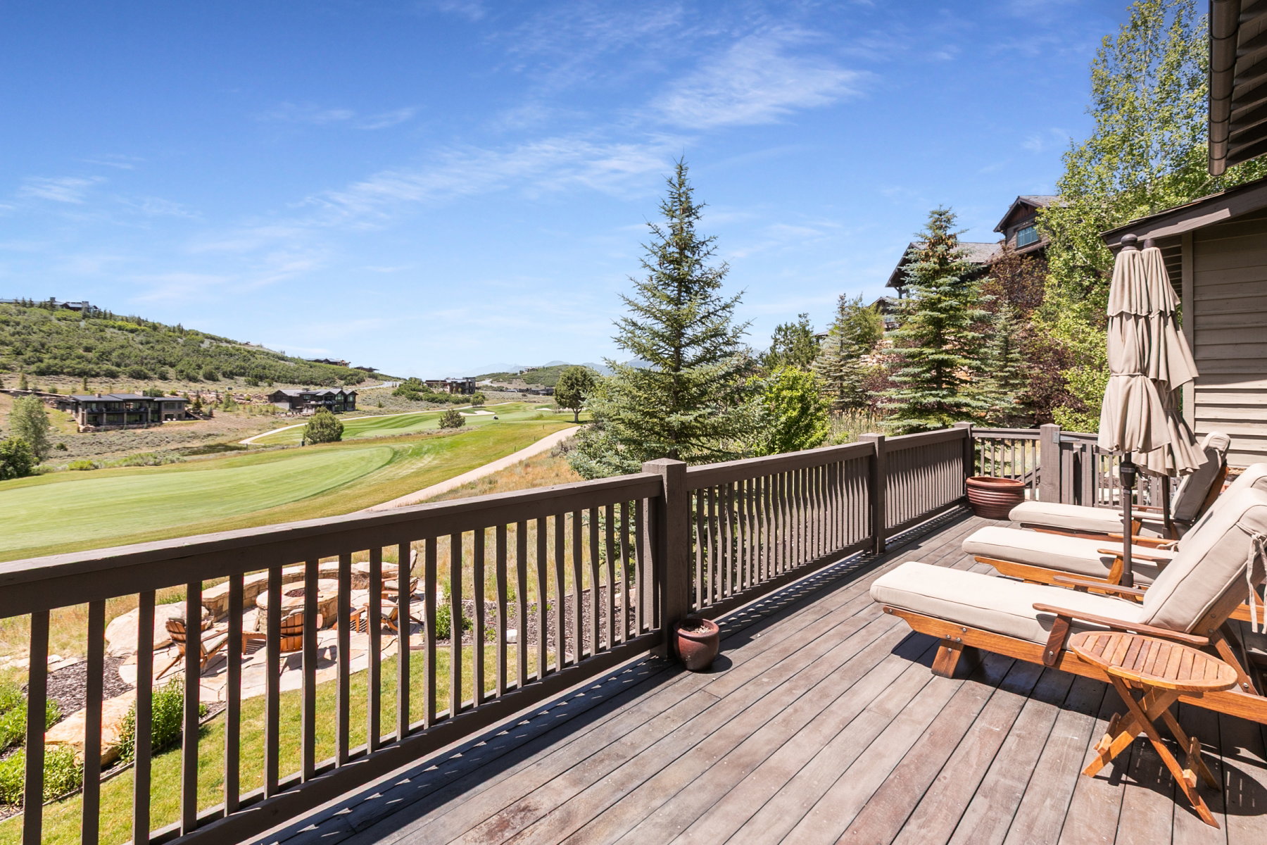 Expansive wood-finish deck with a wood railing overlooking a golf course and distant hills