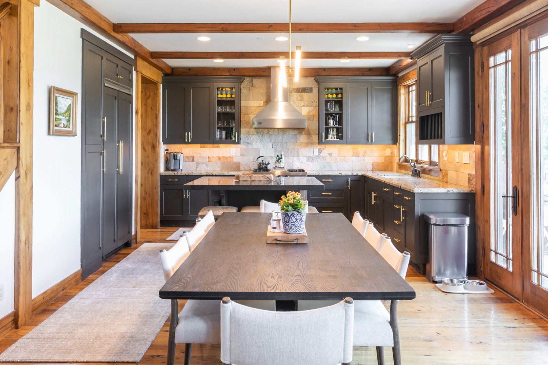 Kitchen featuring dark cabinetry, natural stone backsplash, and granite countertops
