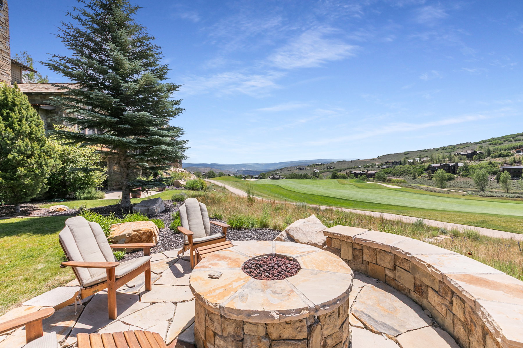 Outdoor patio featuring a flagstone surface, a circular stone fire pit, and a curved stone wall