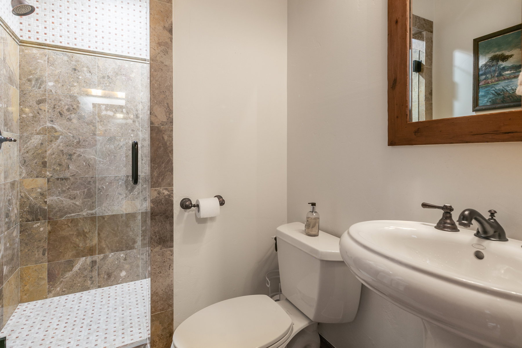 Full bathroom featuring a shower with glass enclosure, large format stone tile walls, and a white penny tile floor