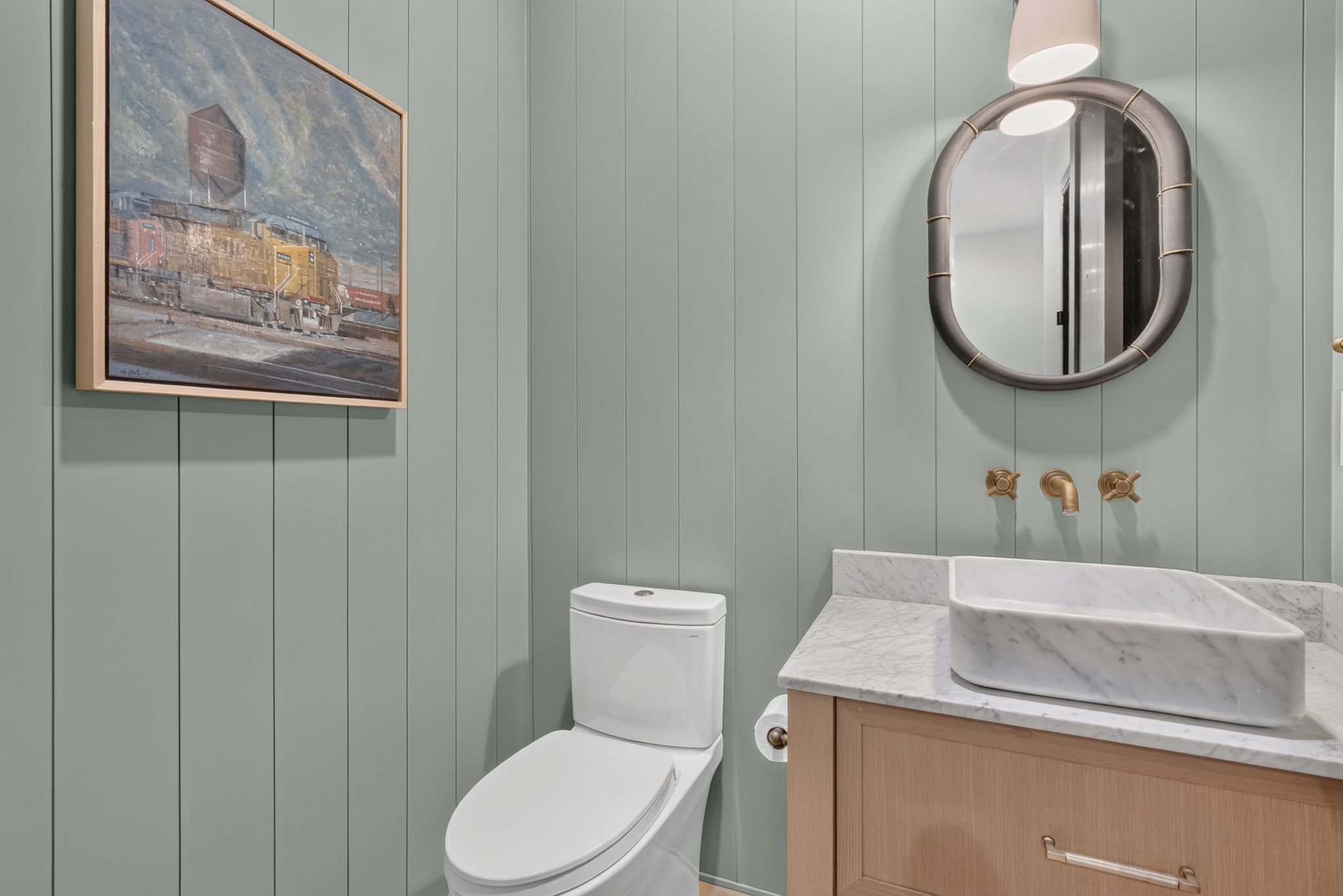 Contemporary powder room featuring vertical paneled walls, a wall-mounted brass faucet, and a stone vessel sink