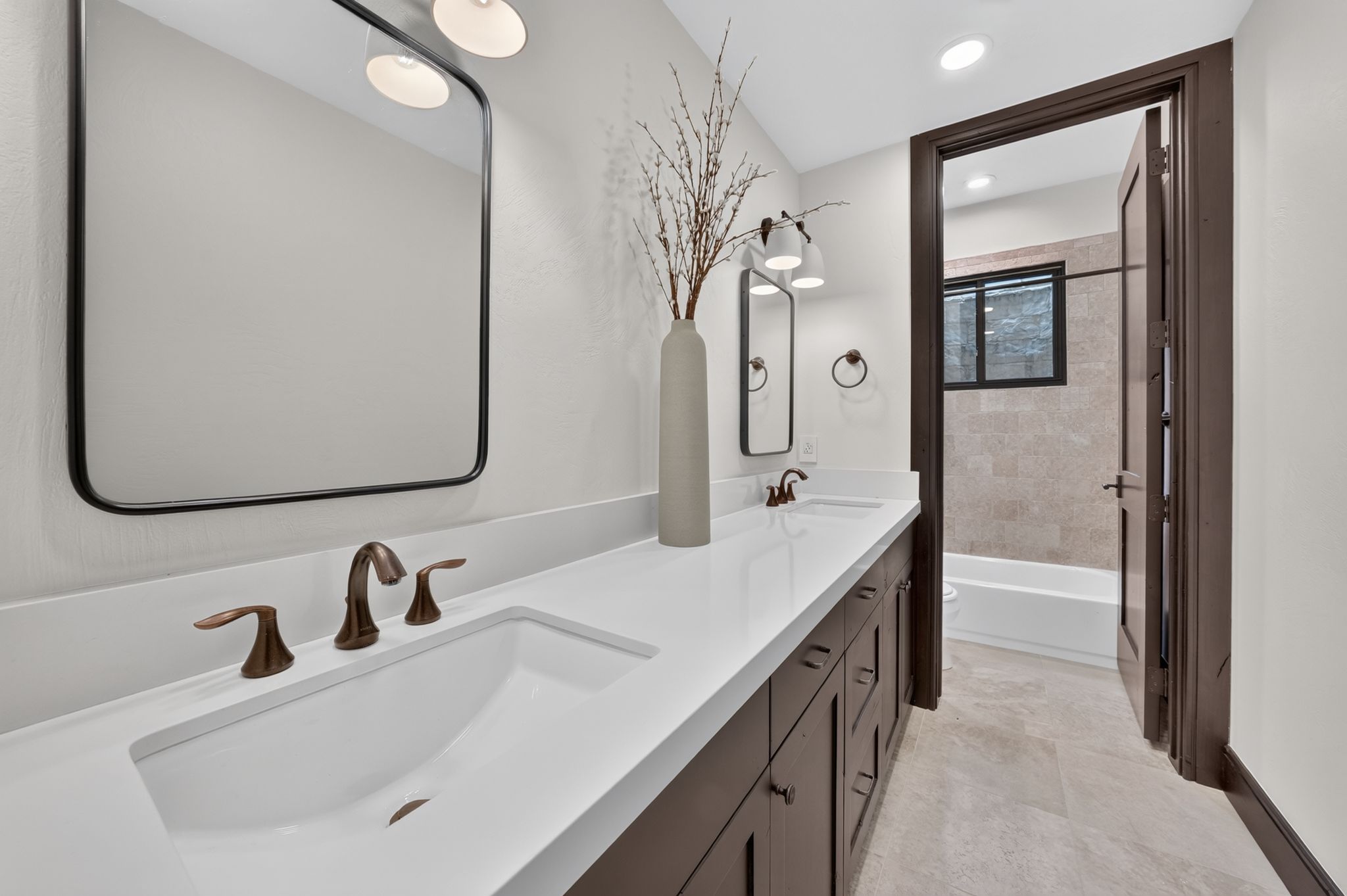 Bathroom featuring a dual vanity with integrated sinks, white countertops, and dark wood cabinetry