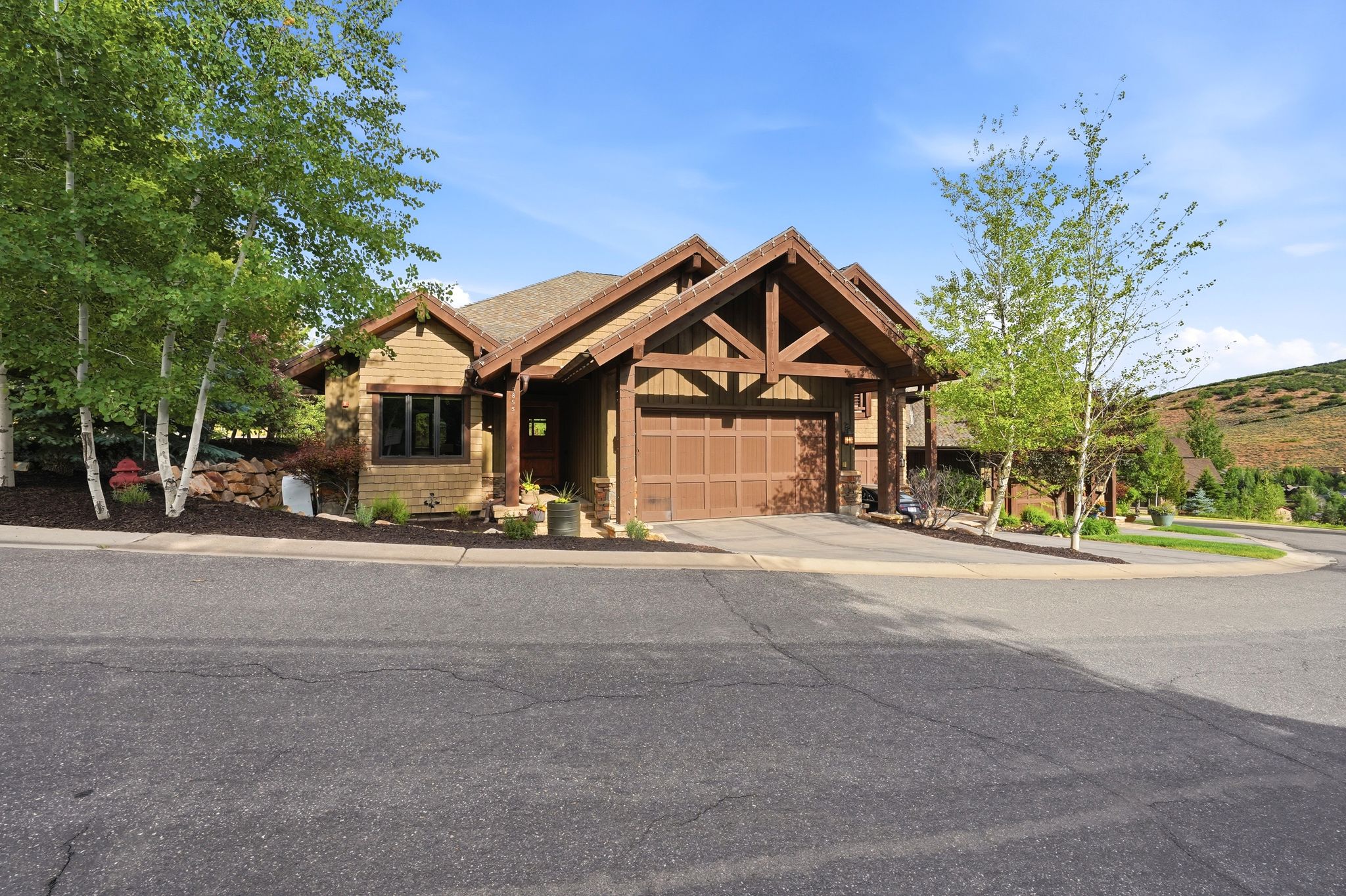 Mountain-style exterior featuring a prominent two-car garage, exposed wood beams, and natural wood siding